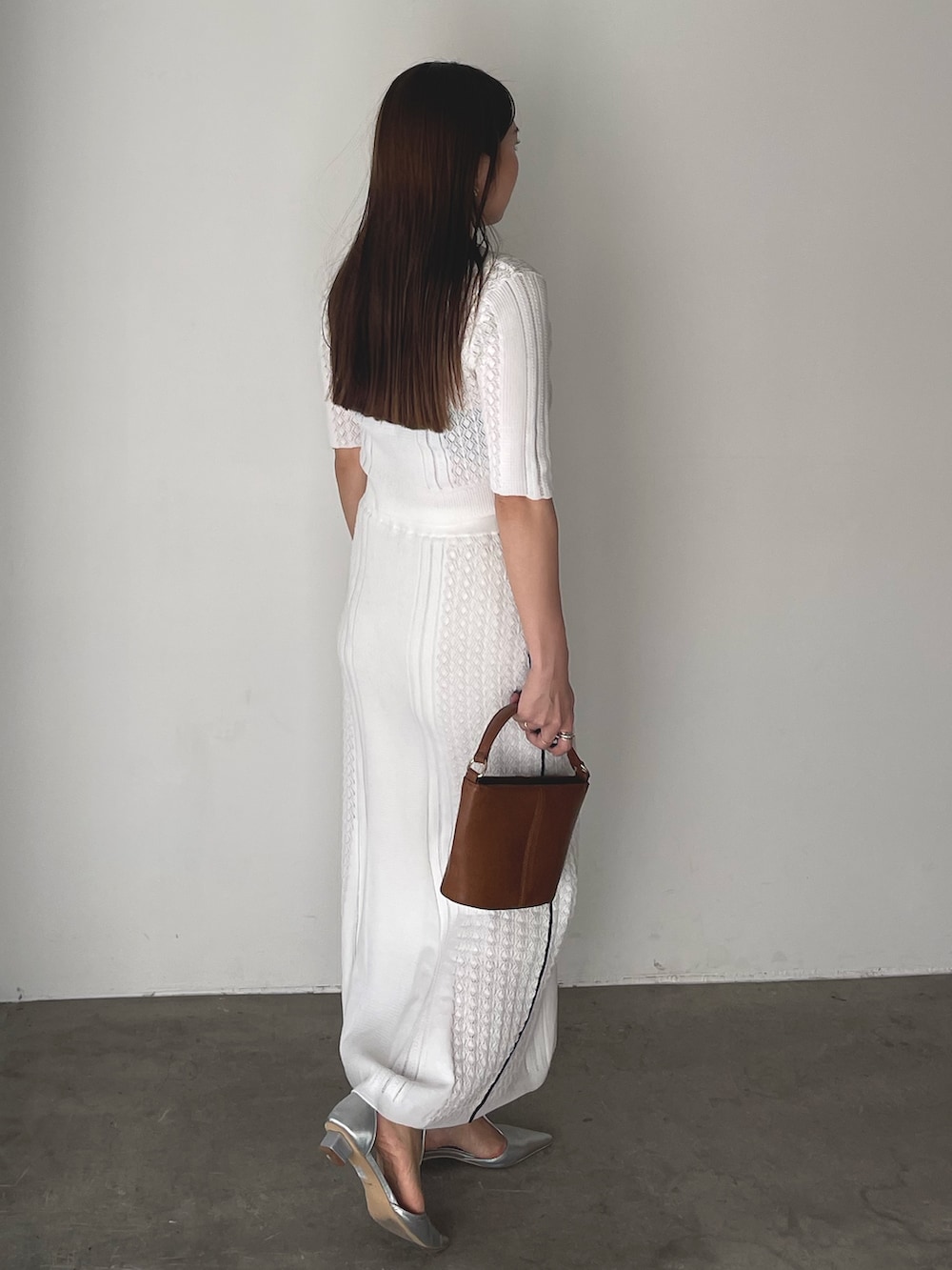 イエロー系のハンドバッグ、シルバー系のパンプス、ホワイト系のワンピースを着用したレディースの冬コーディネートの7枚目の写真