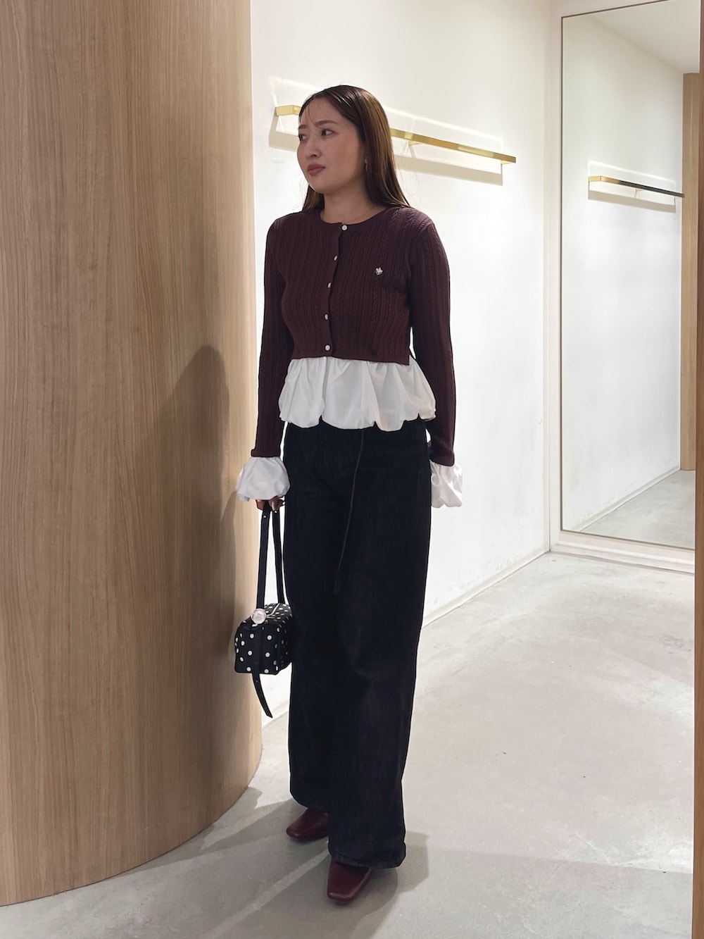 レッド系のブーツ、ブラック系のデニムパンツ、ブラック系のハンドバッグを着用したレディースの秋コーディネートの6枚目の写真
