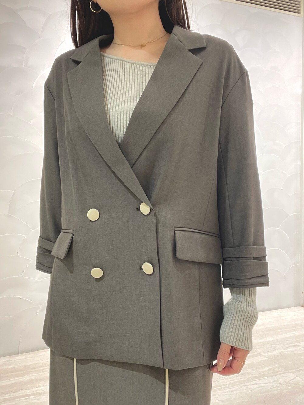 グレー系のスカート、ホワイト系のサンダル、グレー系のニット/セーターを着用したレディースの春コーディネートの6枚目の写真