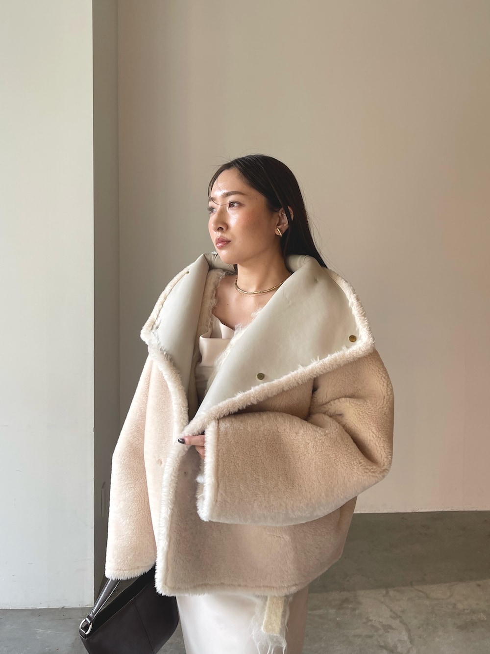 ベージュ系のワンピース、ブラウン系のハンドバッグ、ブラウン系のブーツを着用したレディースの冬コーディネートの9枚目の写真