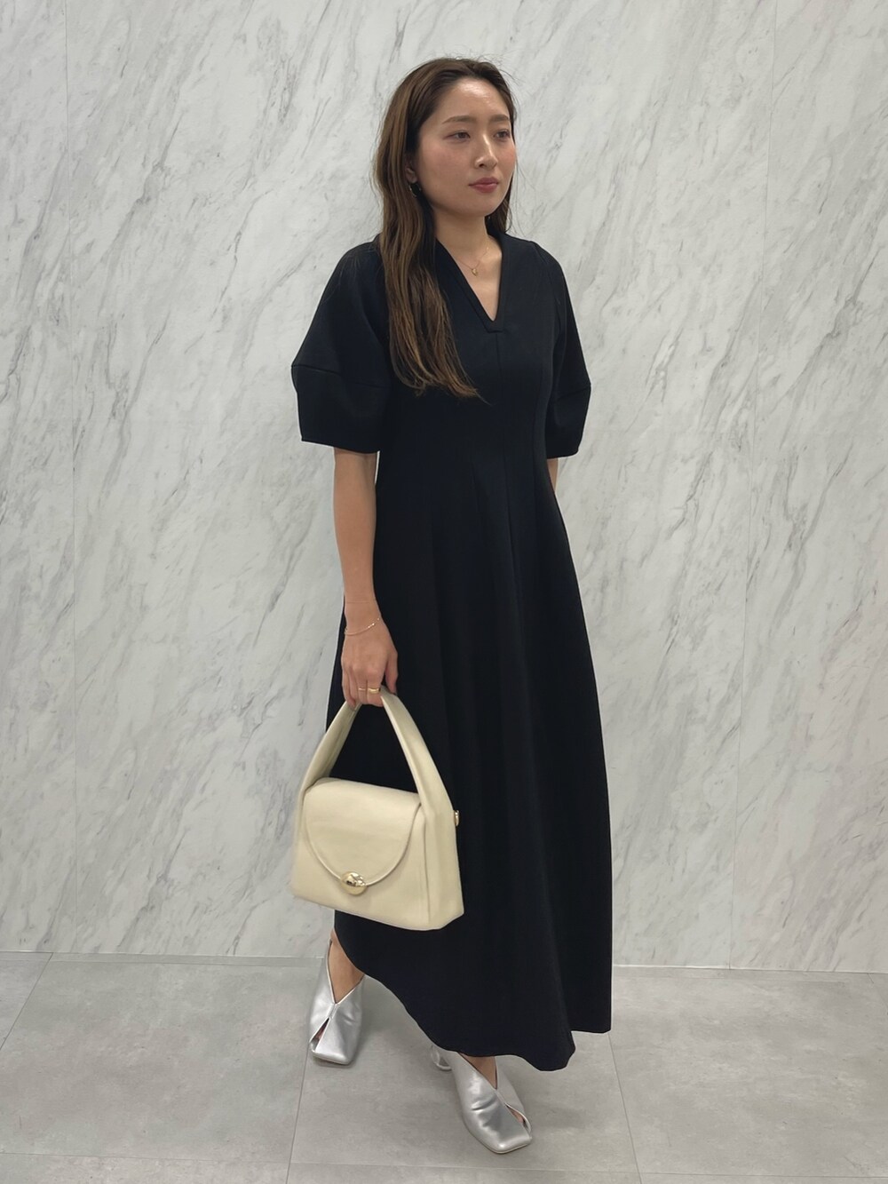 シルバー系のパンプス、ホワイト系のハンドバッグ、ブラック系のパンプスを着用したレディースの冬コーディネートの4枚目の写真