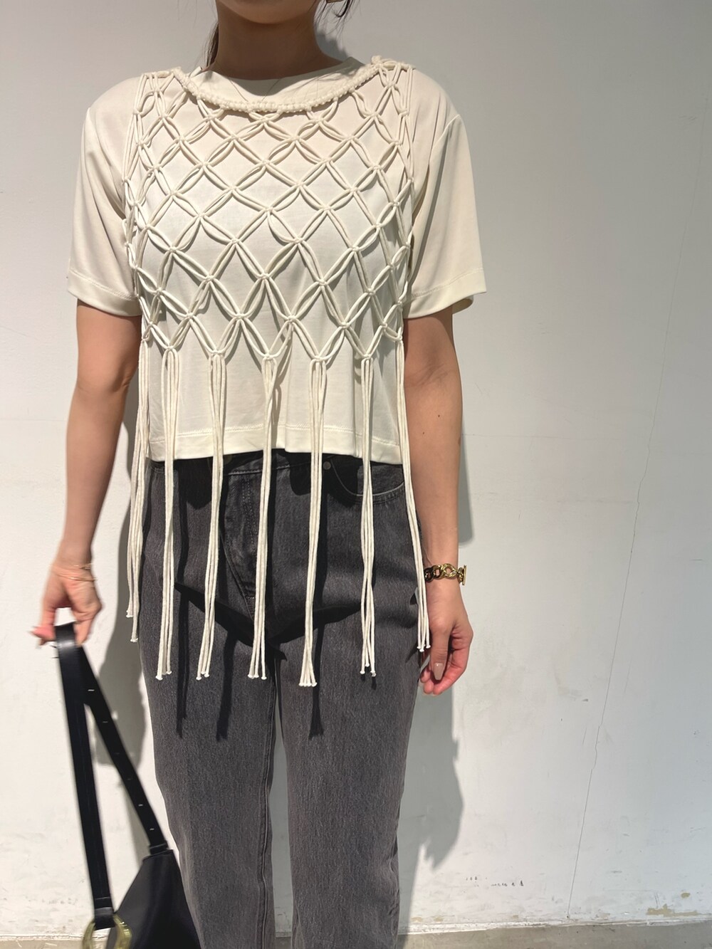 ブラック系のデニムパンツ、ブラック系のサンダル、ブラック系のショルダーバッグを着用したレディースの春コーディネートの5枚目の写真