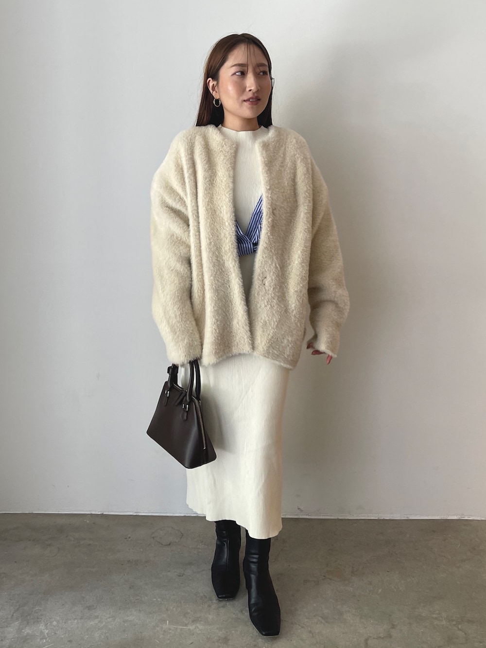 ブラウン系のボストンバッグ、ブラック系のブーツ、ホワイト系のワンピースを着用したレディースの秋コーディネートの2枚目の写真