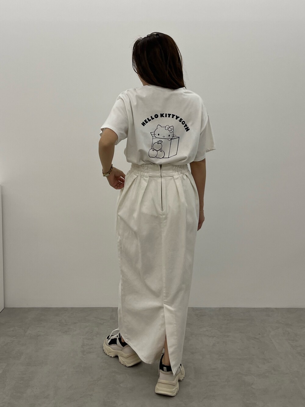 ブラック系のスニーカー、ホワイト系のデニムスカート、ホワイト系のTシャツ/カットソーを着用したレディースの春コーディネートの3枚目の写真