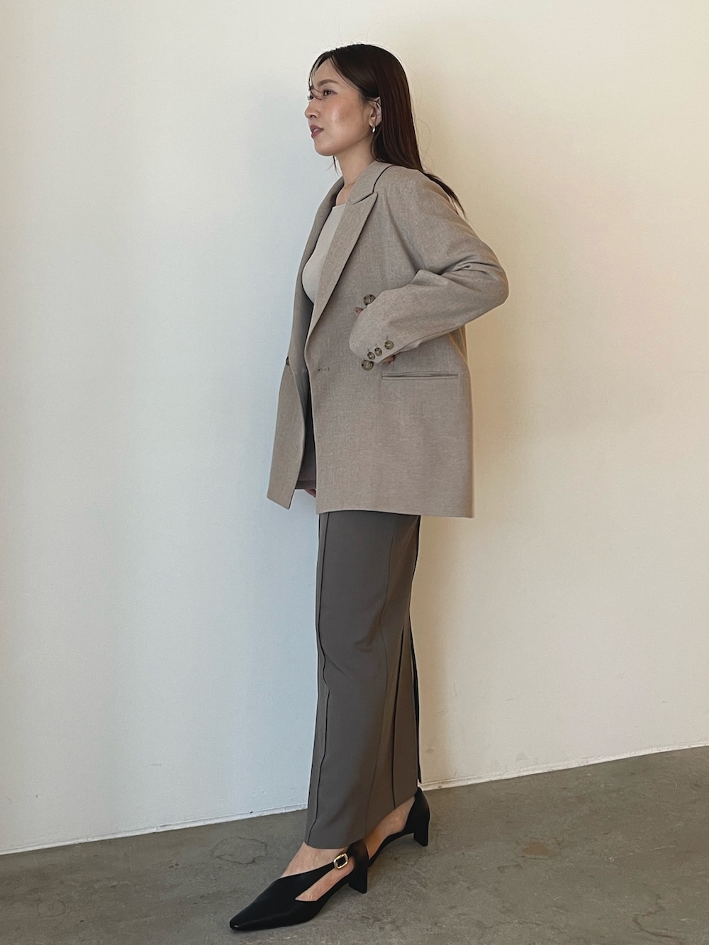 ブラック系のパンプス、グレー系のスカート、ベージュ系のニット/セーターを着用したレディースの秋コーディネートの3枚目の写真