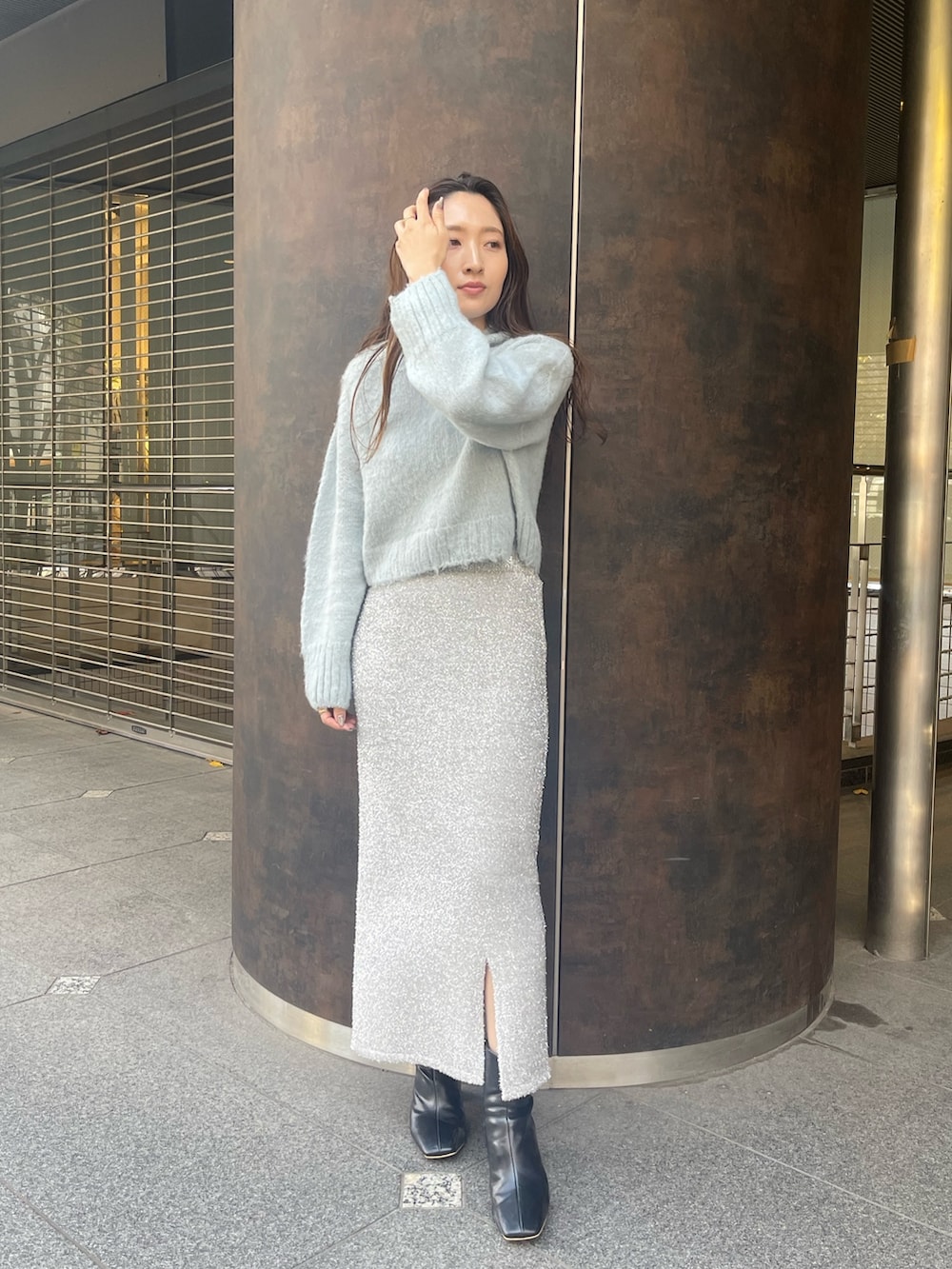 シルバー系のスカート、ブラック系のブーツ、グリーン系のニット/セーターを着用したレディースの冬コーディネートの2枚目の写真