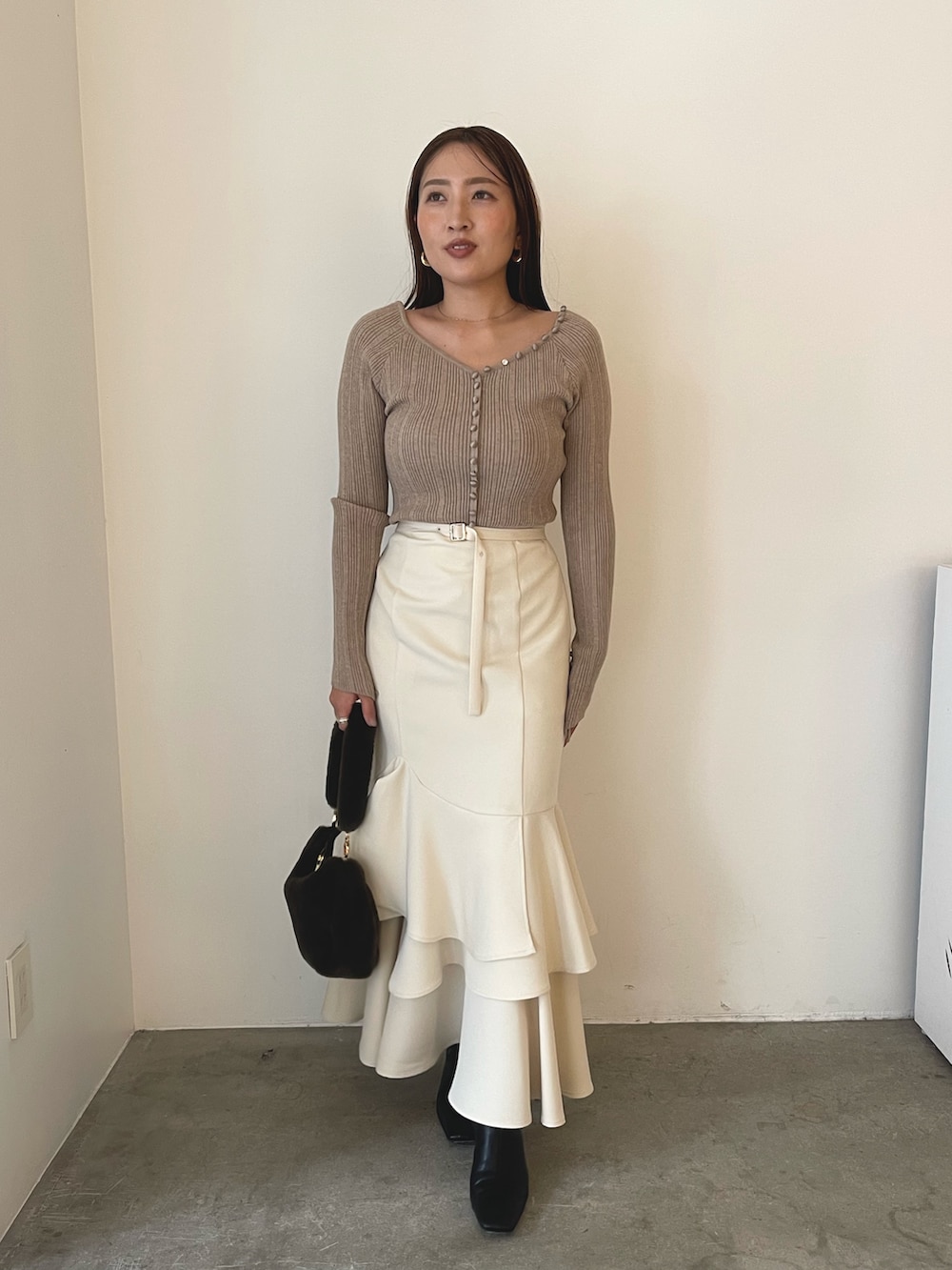 ブラウン系のショルダーバッグ、ブラック系のブーツ、ベージュ系のワンピースを着用したレディースの冬コーディネートの6枚目の写真