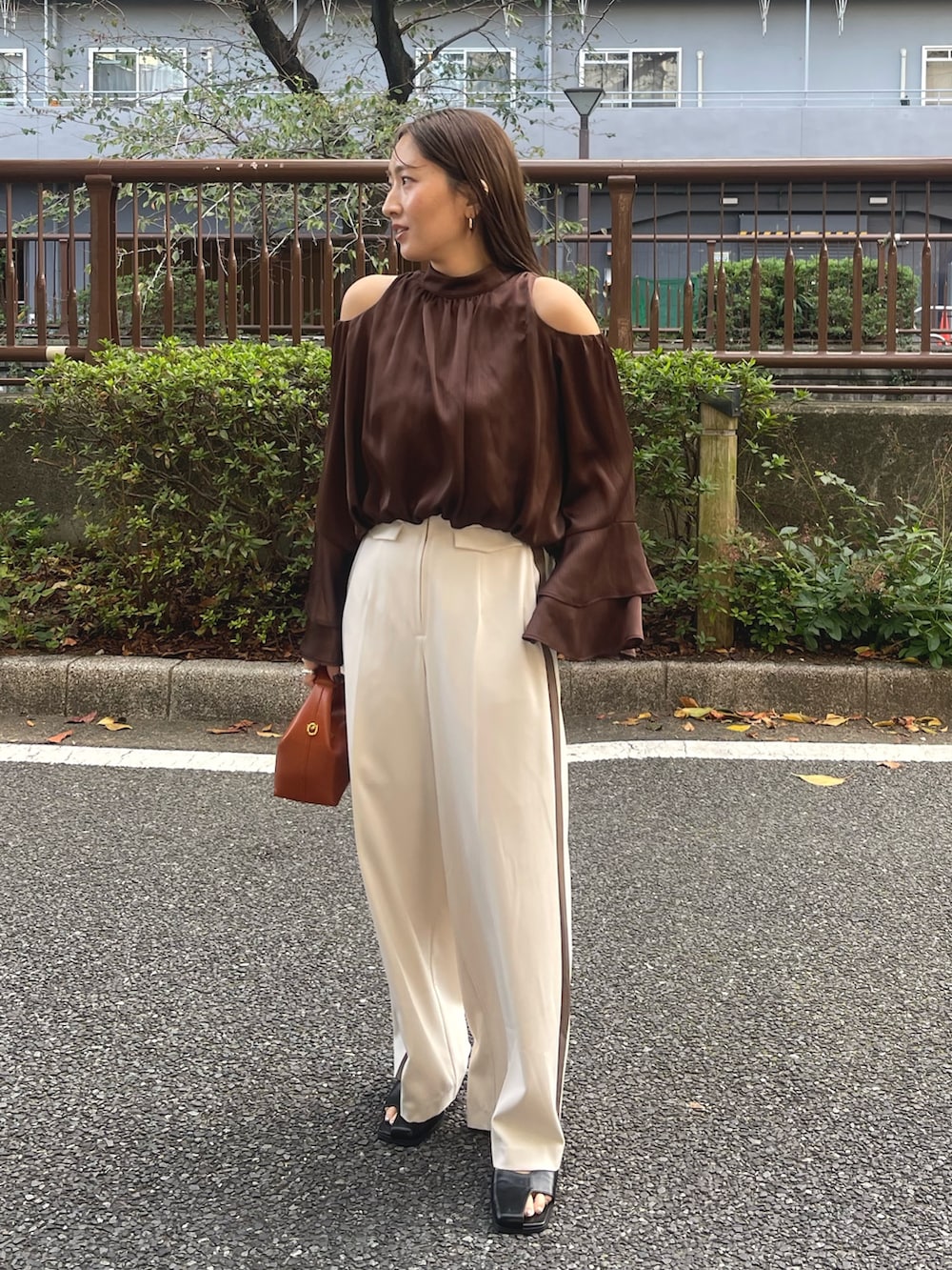 ブラック系のサンダル、ブラウン系のハンドバッグ、ホワイト系のその他パンツを着用したレディースの冬コーディネートの2枚目の写真