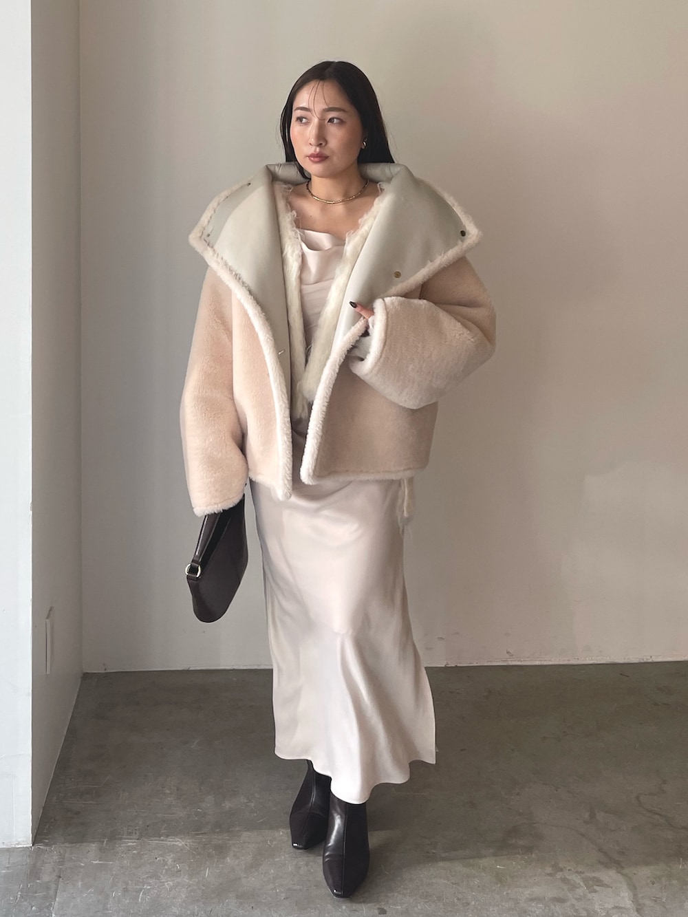 ベージュ系のワンピース、ブラウン系のハンドバッグ、ブラウン系のブーツを着用したレディースの冬コーディネートの3枚目の写真