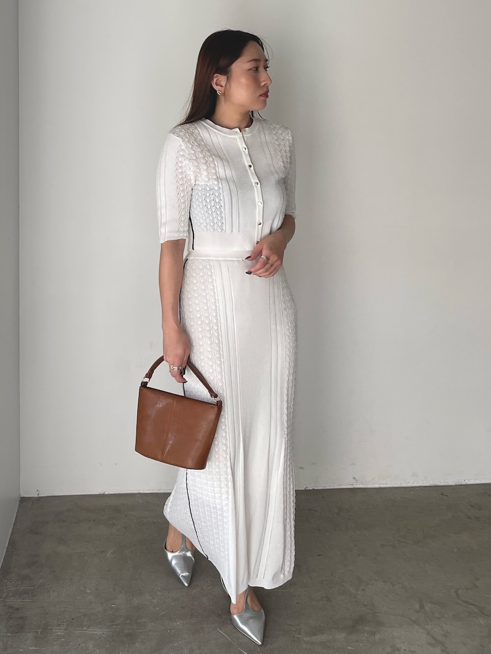 イエロー系のハンドバッグ、シルバー系のパンプス、ホワイト系のワンピースを着用したレディースの冬コーディネートの5枚目の写真