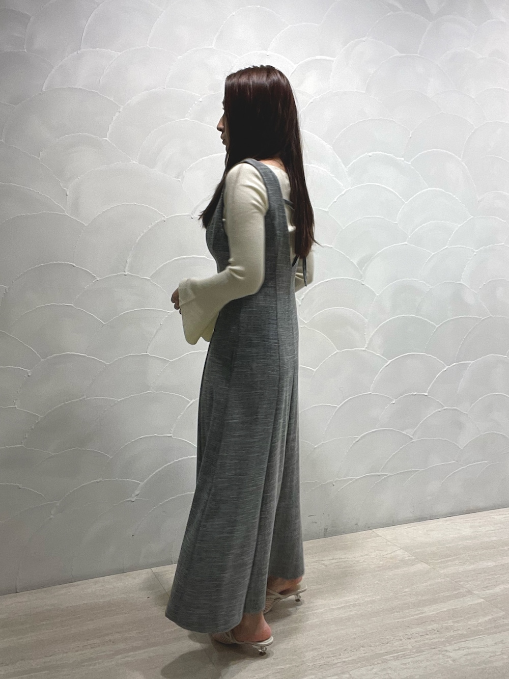 ホワイト系のサンダル、ホワイト系のニット/セーター、グレー系のジャンパースカートを着用したレディースの春コーディネートの3枚目の写真