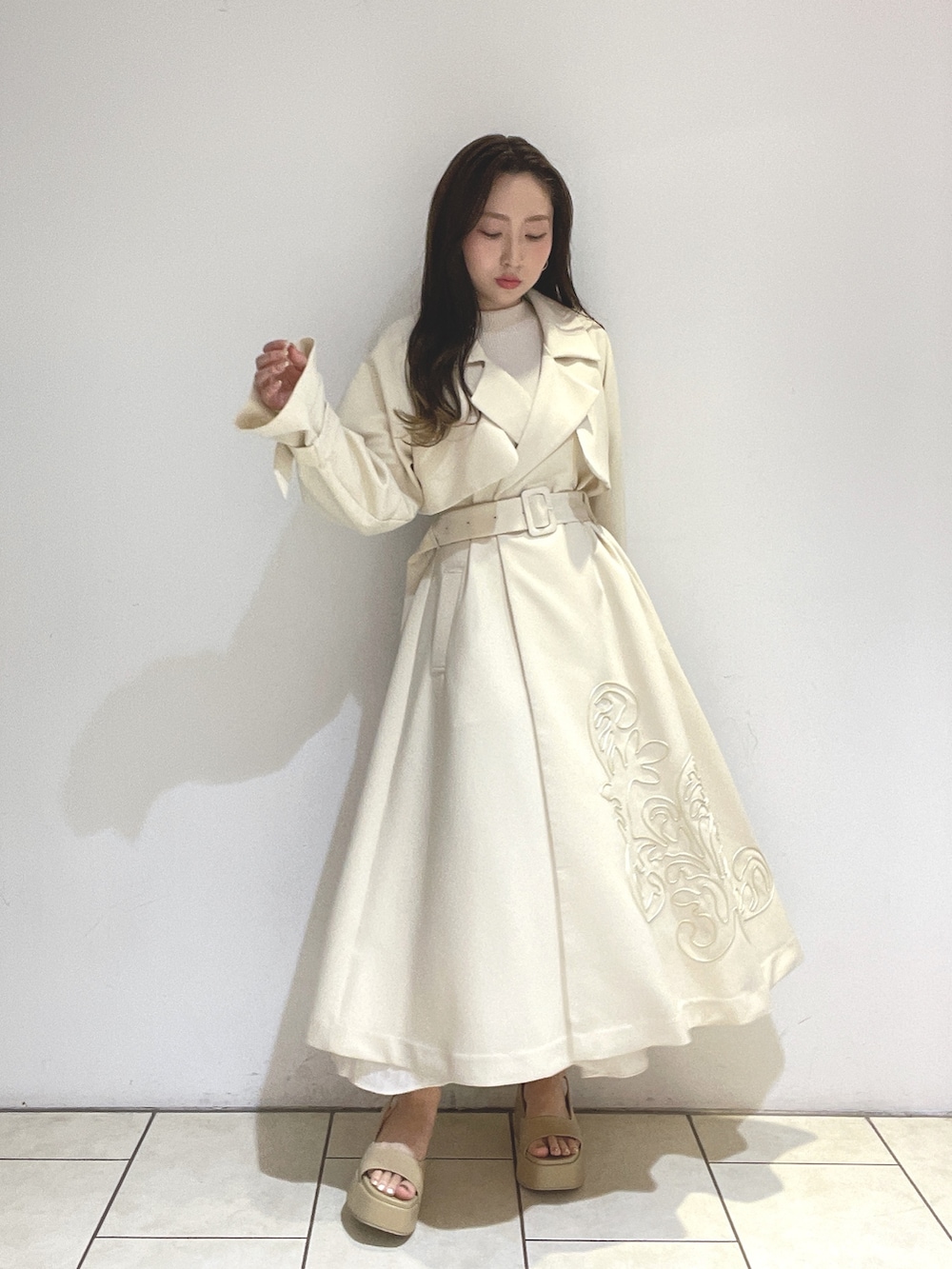 ホワイト系のトレンチコート、ベージュ系のサンダル、グリーン系のショルダーバッグを着用したレディースの冬コーディネートの5枚目の写真