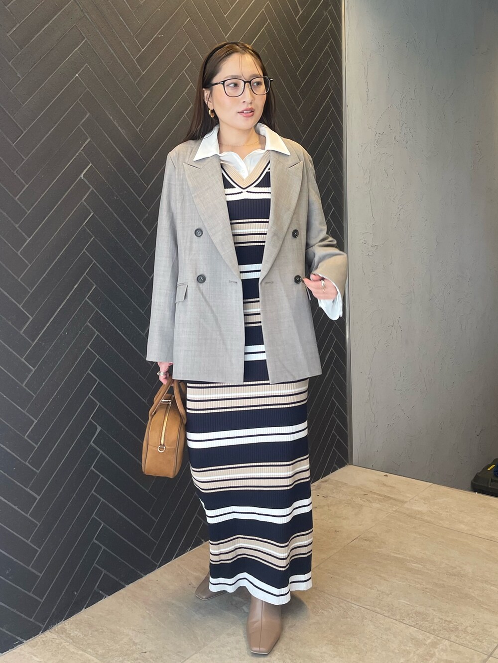 イエロー系のハンドバッグ、ベージュ系のワンピース、グレー系のテーラードジャケットを着用したレディースの冬コーディネートの3枚目の写真