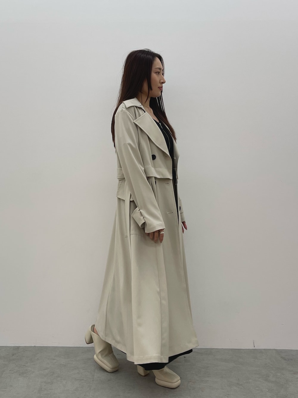 ホワイト系のトレンチコート、ブラック系のワンピース、ホワイト系のサンダルを着用したレディースの春コーディネートの4枚目の写真