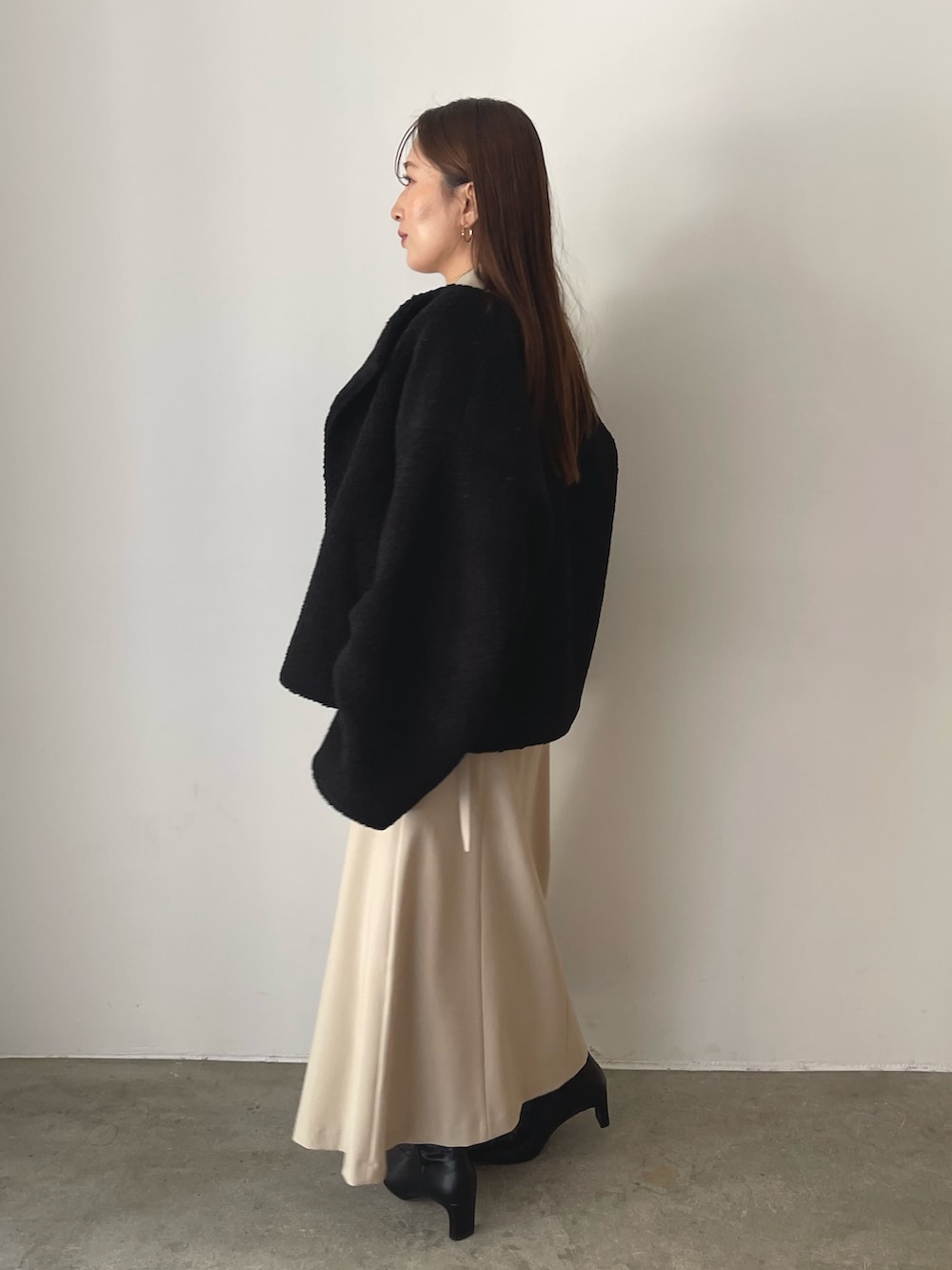 イエロー系のハンドバッグ、ブラック系のブルゾン、ベージュ系のワンピースを着用したレディースの秋コーディネートの3枚目の写真