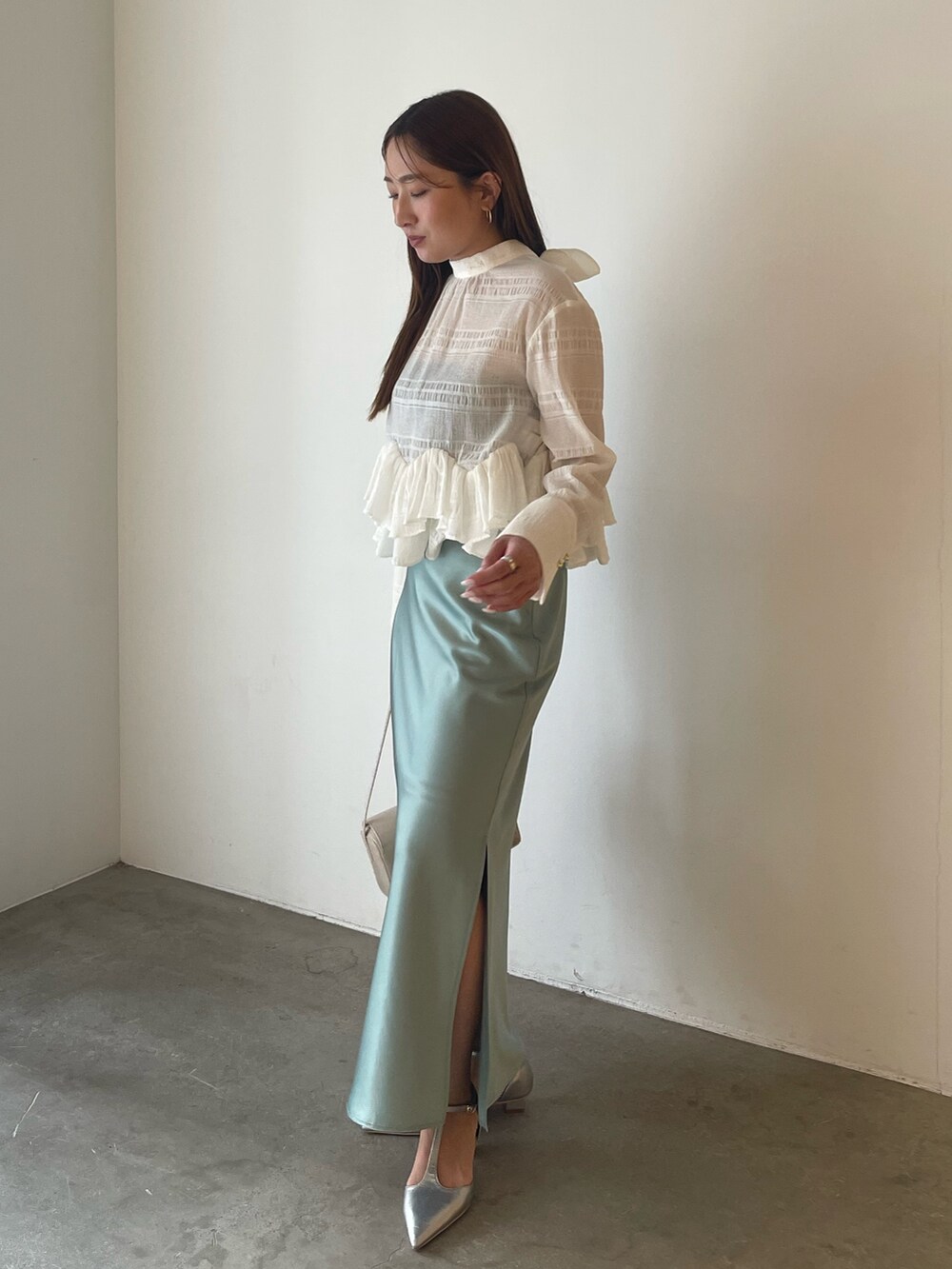 シルバー系のパンプス、ホワイト系のシャツ/ブラウス、グリーン系のスカートを着用したレディースの冬コーディネートの2枚目の写真