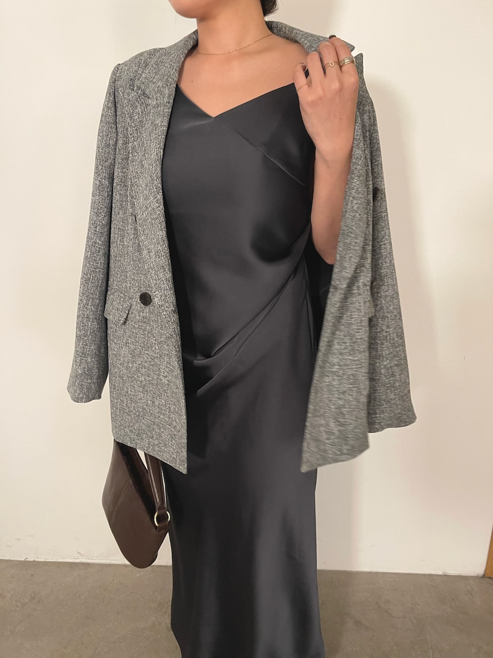 グレー系のドレス、ブラウン系のハンドバッグ、ゴールド系のパンプスを着用したレディースの冬コーディネートの9枚目の写真