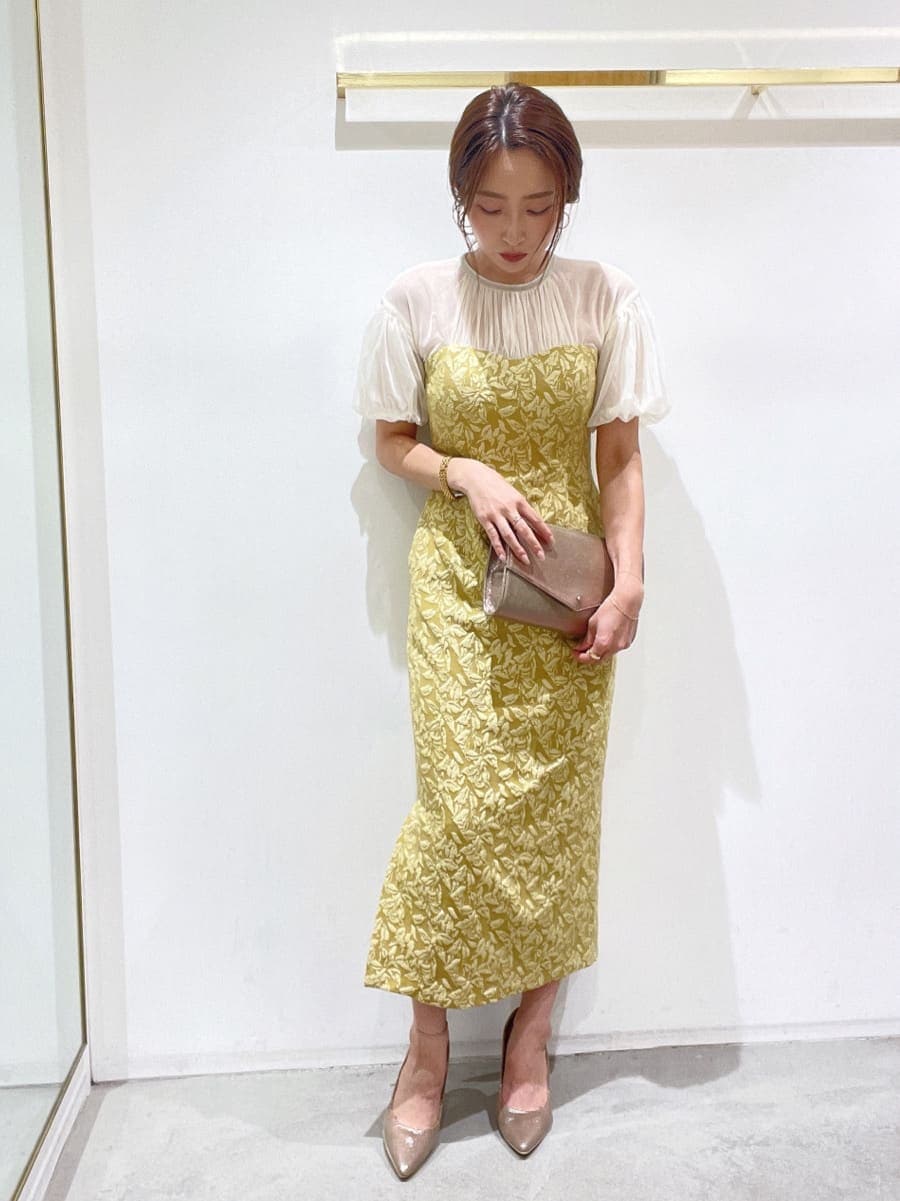ゴールド系のクラッチバッグ、ゴールド系のパンプス、イエロー系のドレスを着用したレディースの秋コーディネートの3枚目の写真