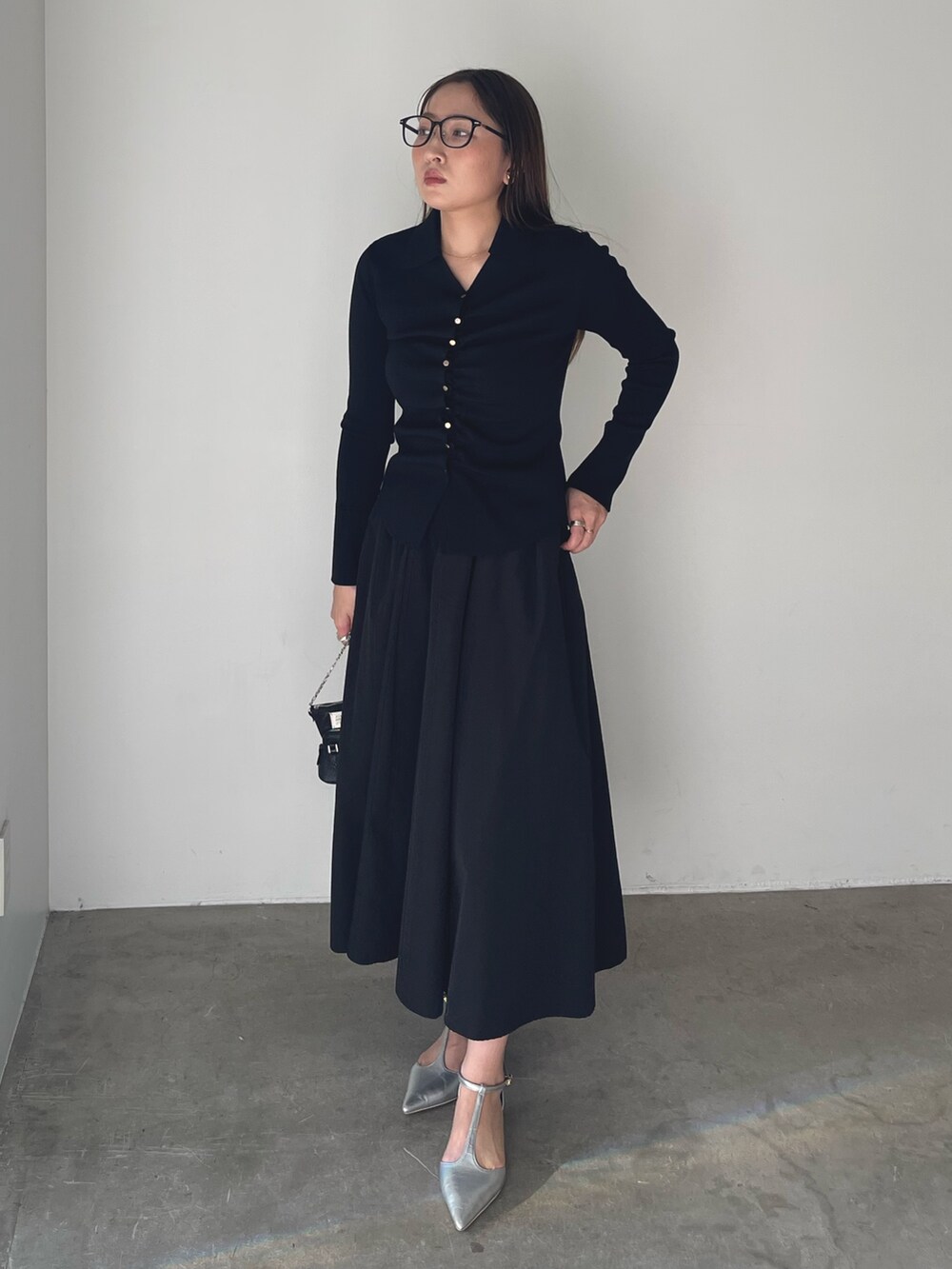 シルバー系のパンプス、ブラック系のワンピース、ゴールド系のピアス（両耳用）を着用したレディースの冬コーディネートの4枚目の写真