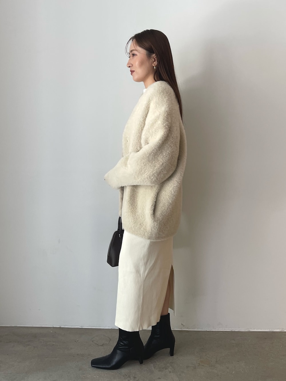 ブラウン系のボストンバッグ、ブラック系のブーツ、ホワイト系のワンピースを着用したレディースの秋コーディネートの6枚目の写真