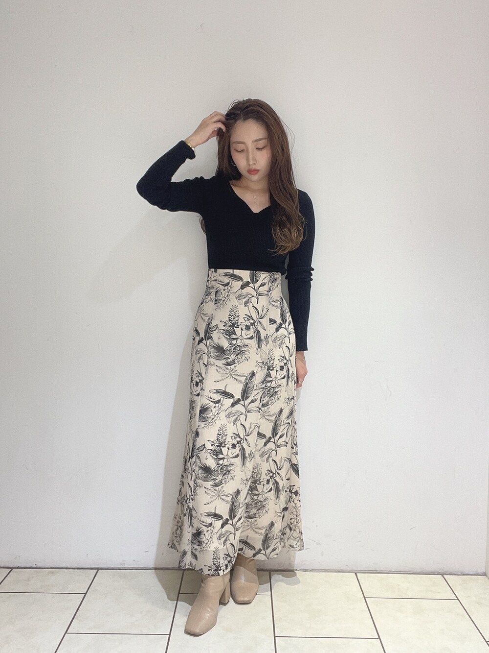 ベージュ系のスカート、ブラック系のニット/セーターを着用したレディースの秋コーディネートの2枚目の写真