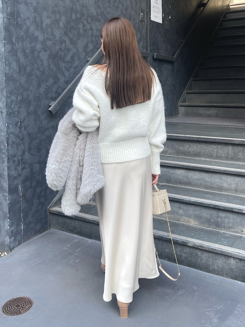 ホワイト系のニット/セーター、グレー系のその他アウター、ゴールド系のハンドバッグを着用したレディースの冬コーディネートの5枚目の写真
