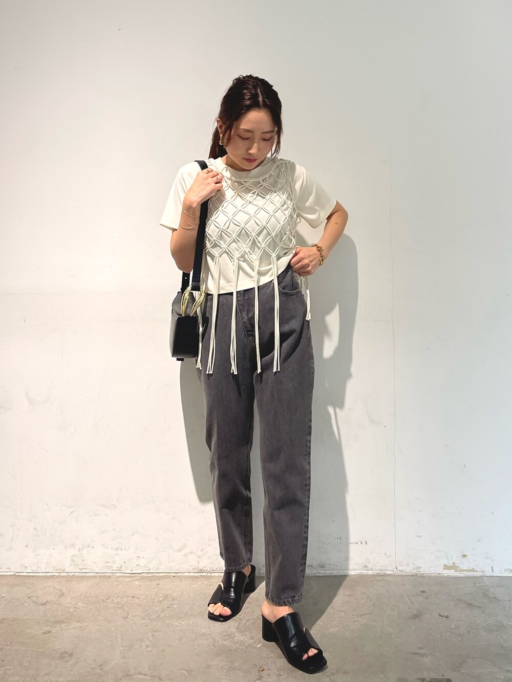 ブラック系のデニムパンツ、ブラック系のサンダル、ブラック系のショルダーバッグを着用したレディースの春コーディネートの2枚目の写真