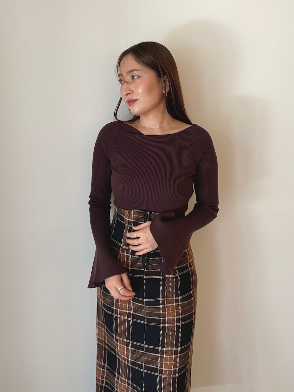 ブラウン系のニット/セーター、ブラウン系のスカート、ブラック系のブーツを着用したレディースの秋コーディネートの10枚目の写真