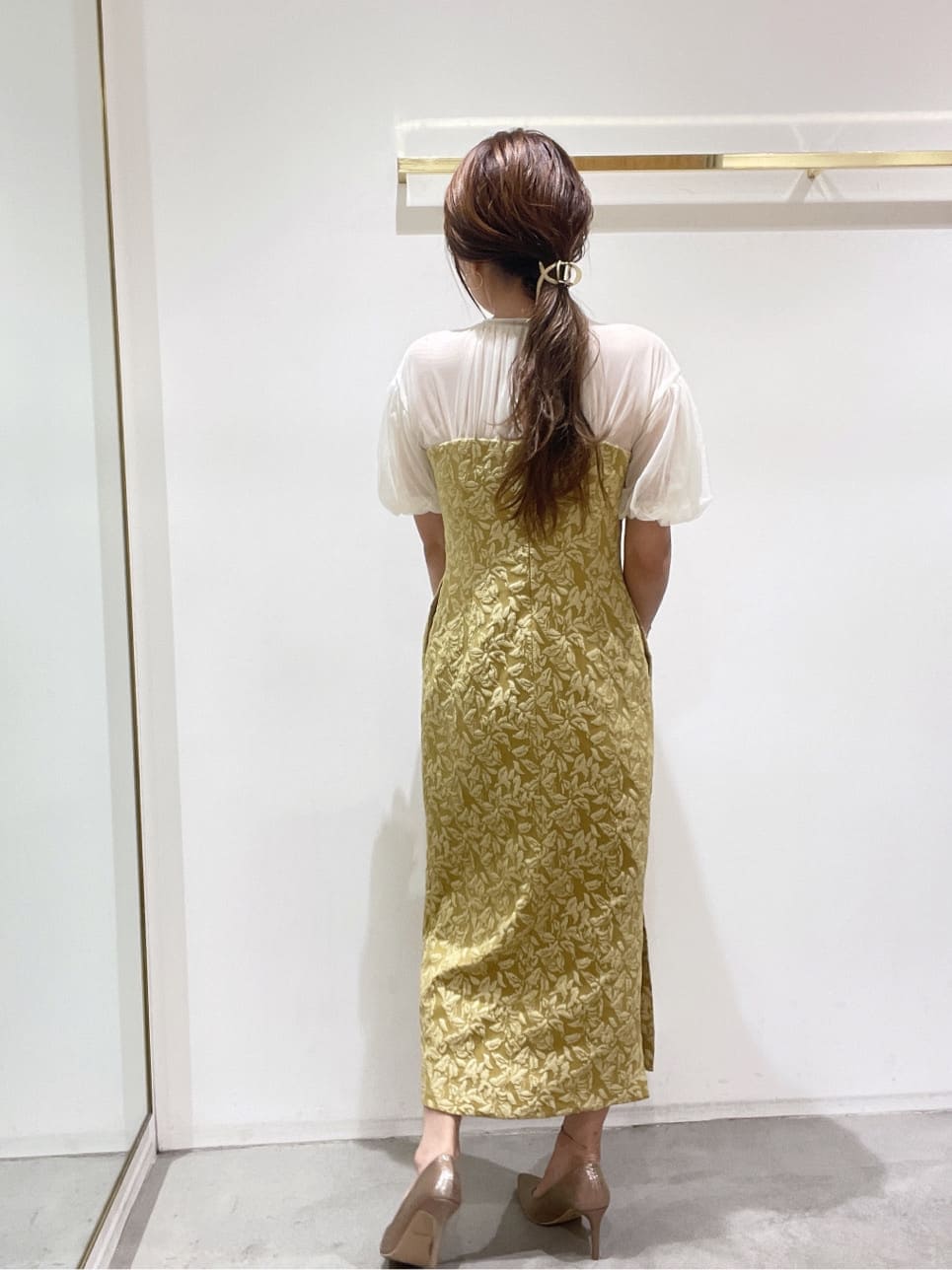 ゴールド系のクラッチバッグ、ゴールド系のパンプス、イエロー系のドレスを着用したレディースの秋コーディネートの5枚目の写真