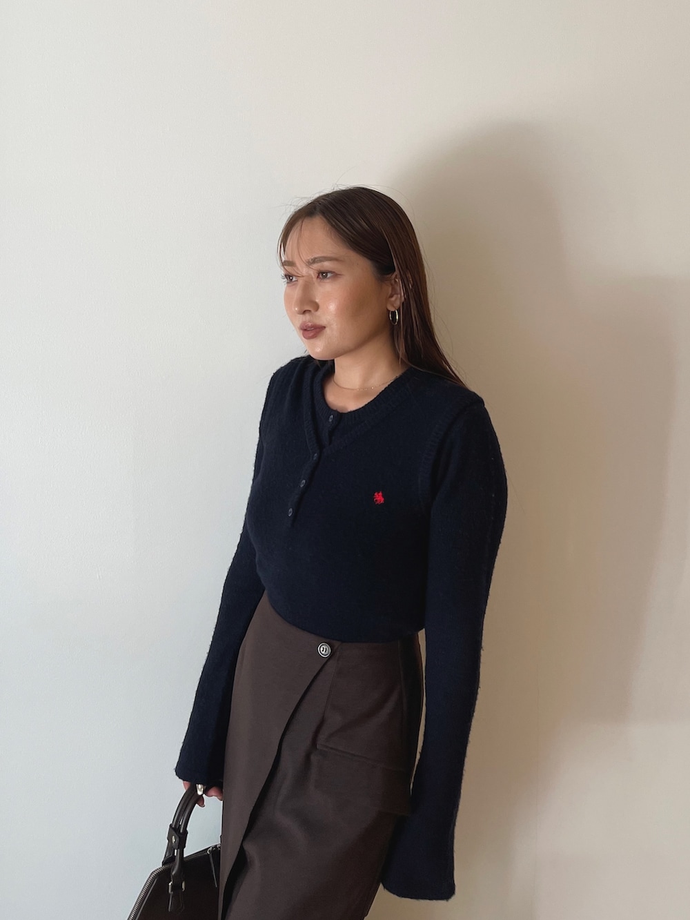 ブラウン系のボストンバッグ、ブラウン系のスカート、ブルー系のニット/セーターを着用したレディースの夏コーディネートの7枚目の写真