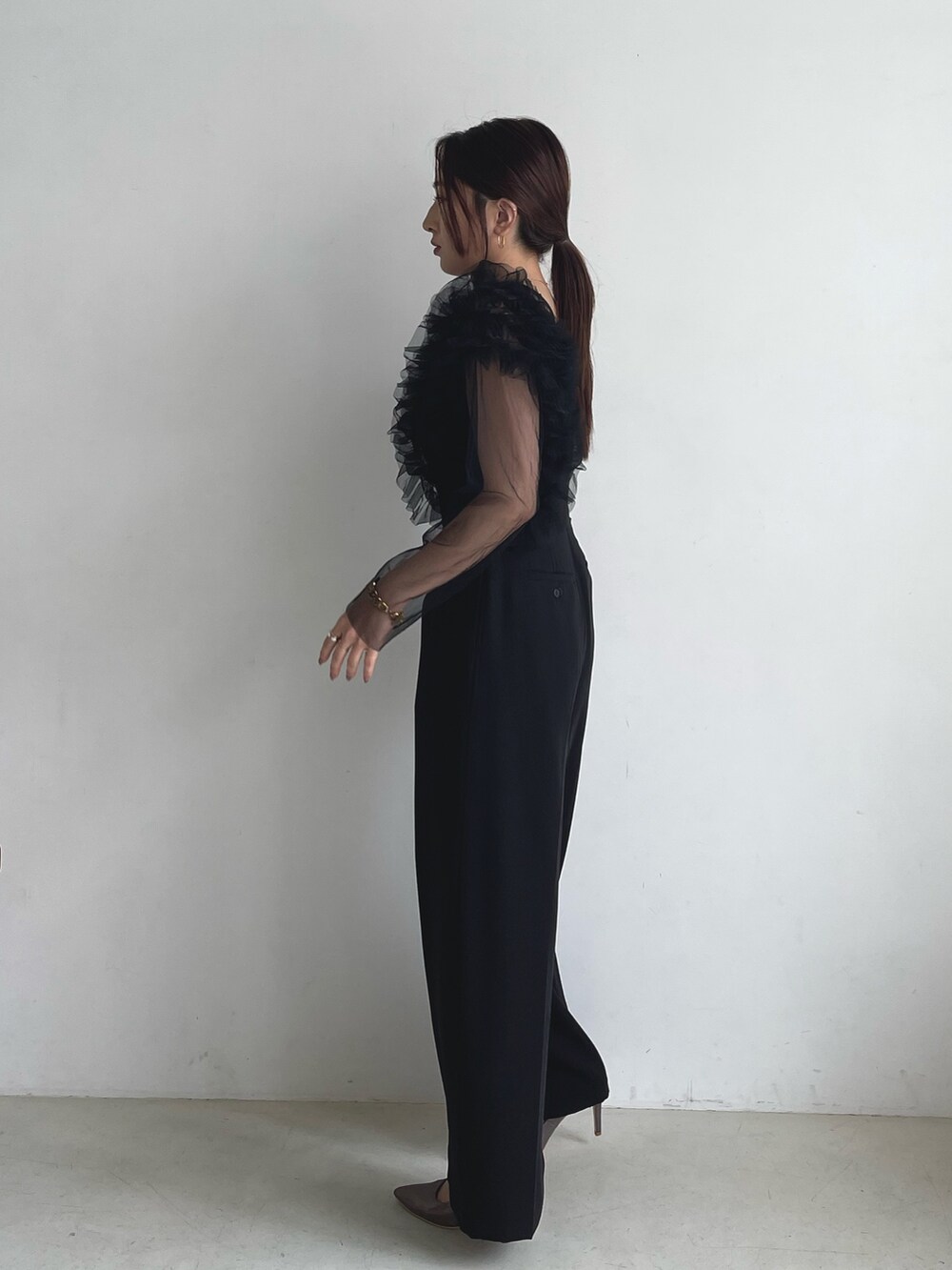 ブラック系のパンツドレス、シルバー系のパンプスを着用したレディースの秋コーディネートの5枚目の写真