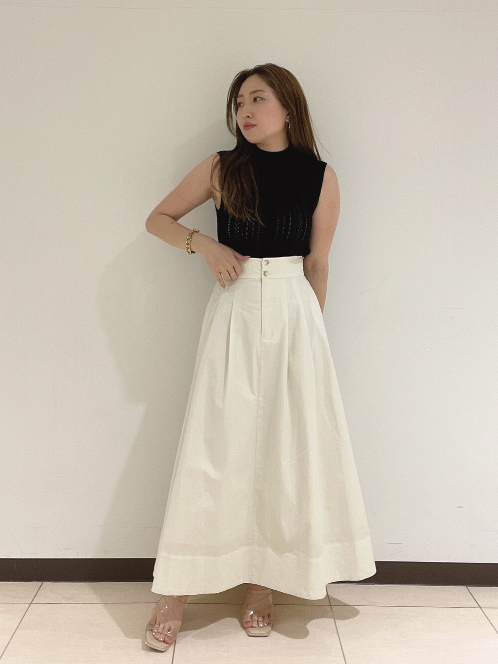 ブラック系のニット/セーター、ホワイト系のスカート、その他のサンダルを着用したレディースの夏コーディネートの3枚目の写真