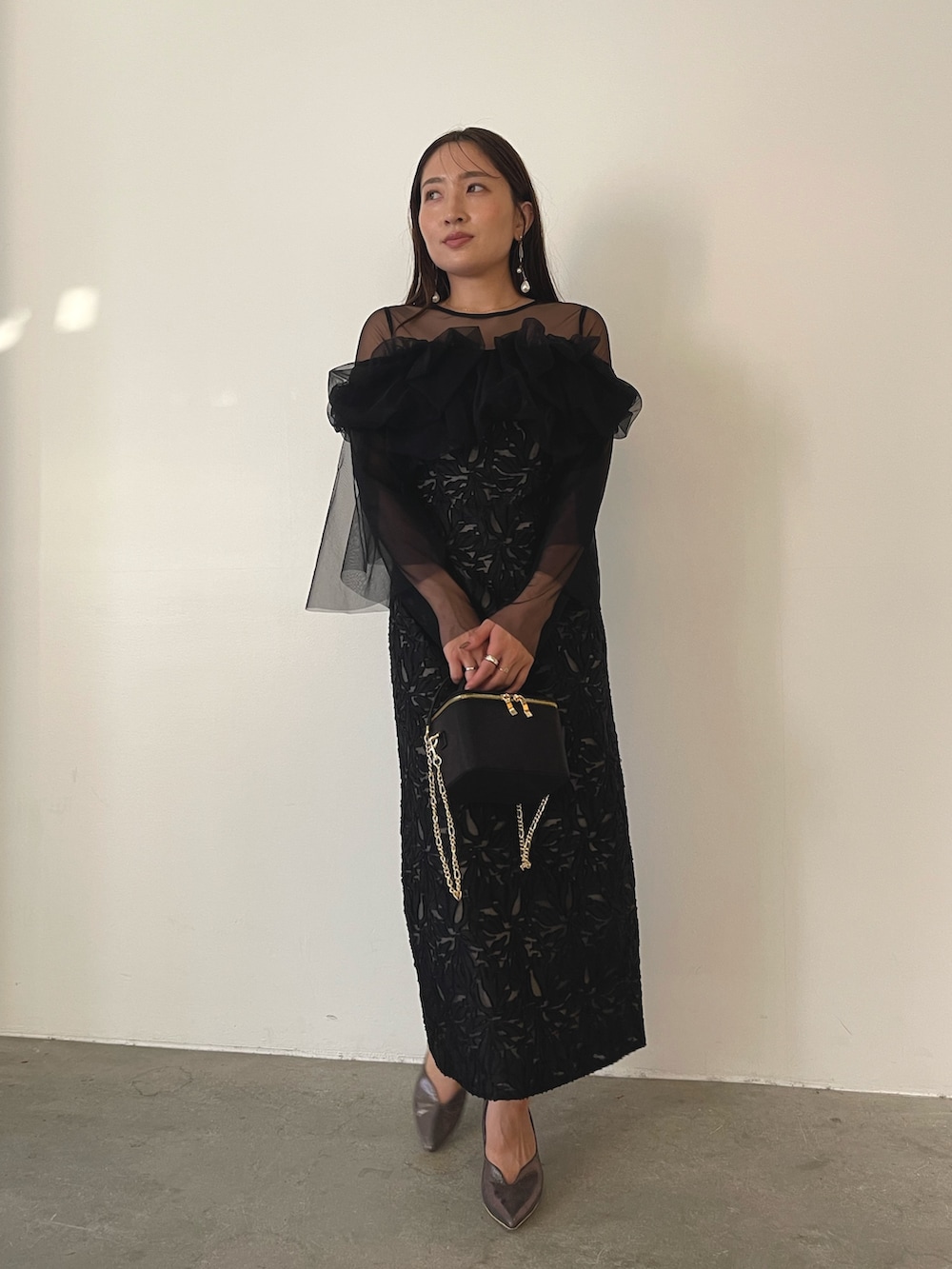 シルバー系のパンプス、ブラック系のハンドバッグ、ブラック系のドレスを着用したレディースの秋コーディネートの7枚目の写真