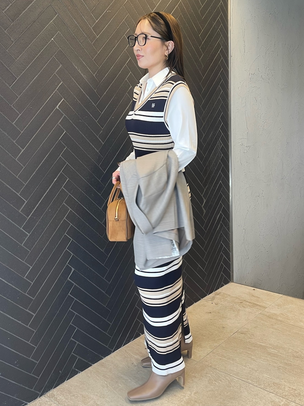 イエロー系のハンドバッグ、ベージュ系のブーツ、グレー系のテーラードジャケットを着用したレディースの冬コーディネートの5枚目の写真