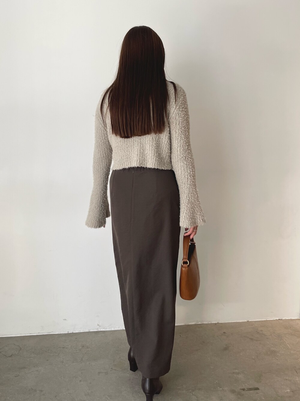 グレー系のアンサンブル、イエロー系のハンドバッグ、ブラウン系のスカートを着用したレディースの秋コーディネートの5枚目の写真