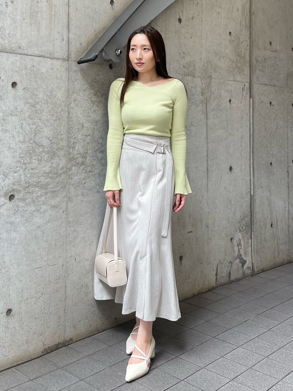 ホワイト系のショルダーバッグ、ホワイト系のパンプス、グレー系のスカートを着用したレディースの秋コーディネートの4枚目の写真