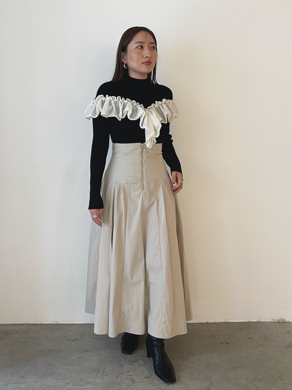 ブラック系のブーツ、ホワイト系のスカート、ブラック系のニット/セーターを着用したレディースの秋コーディネートの7枚目の写真