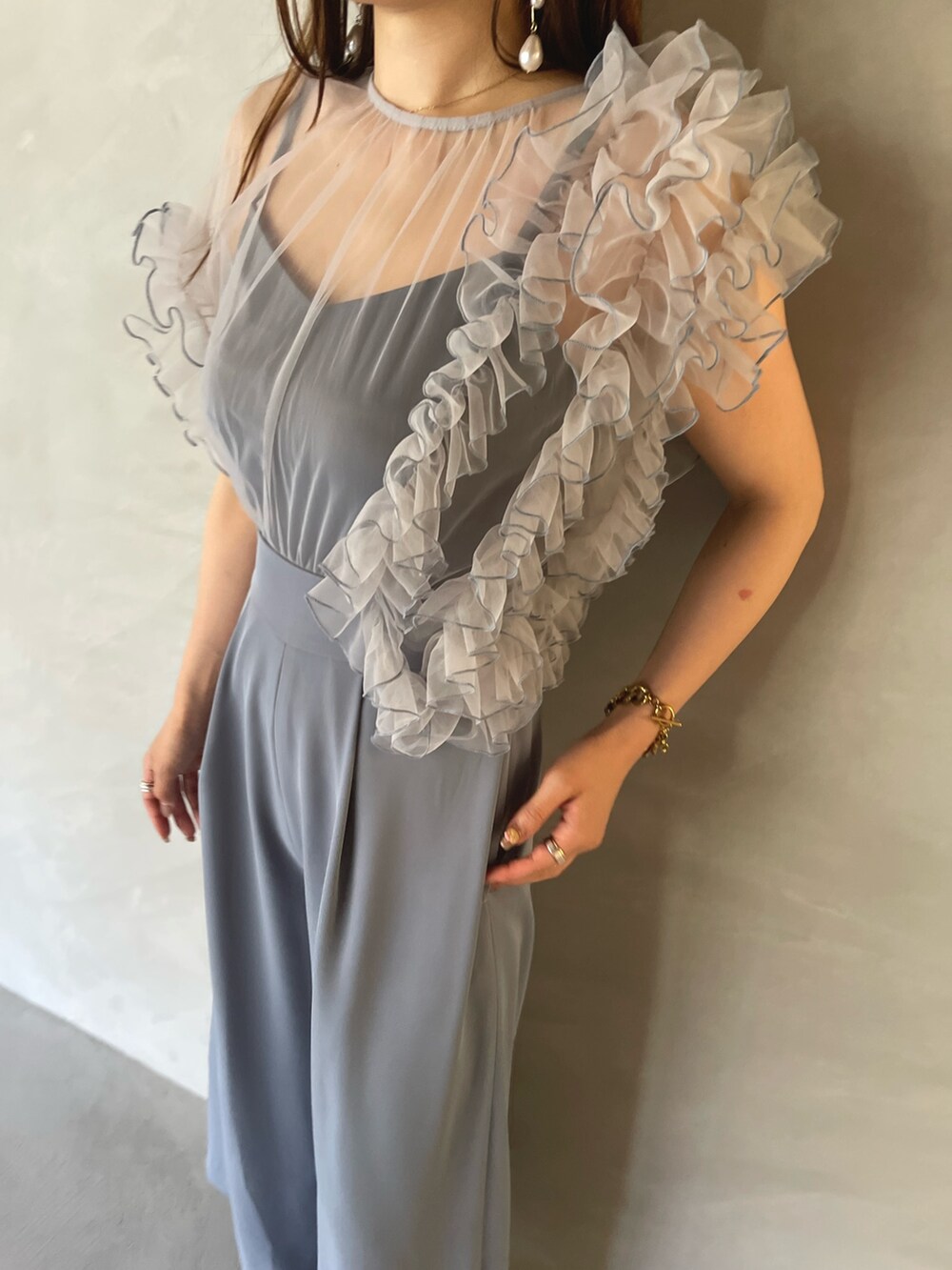 ブルー系のパンツドレス、ゴールド系のピアス（両耳用）を着用したレディースの夏コーディネートの9枚目の写真