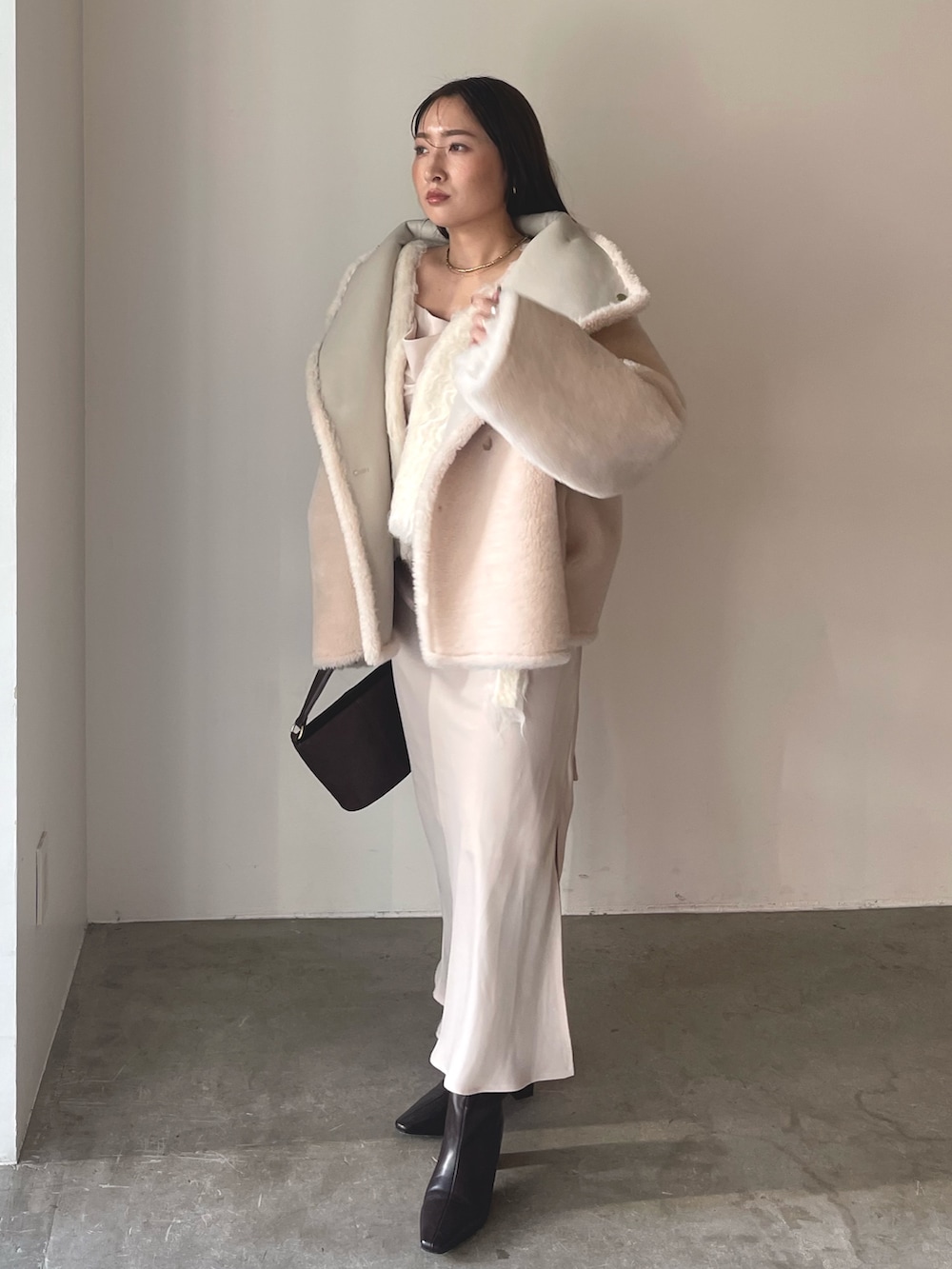 ベージュ系のワンピース、ブラウン系のハンドバッグ、ブラウン系のブーツを着用したレディースの冬コーディネートの2枚目の写真