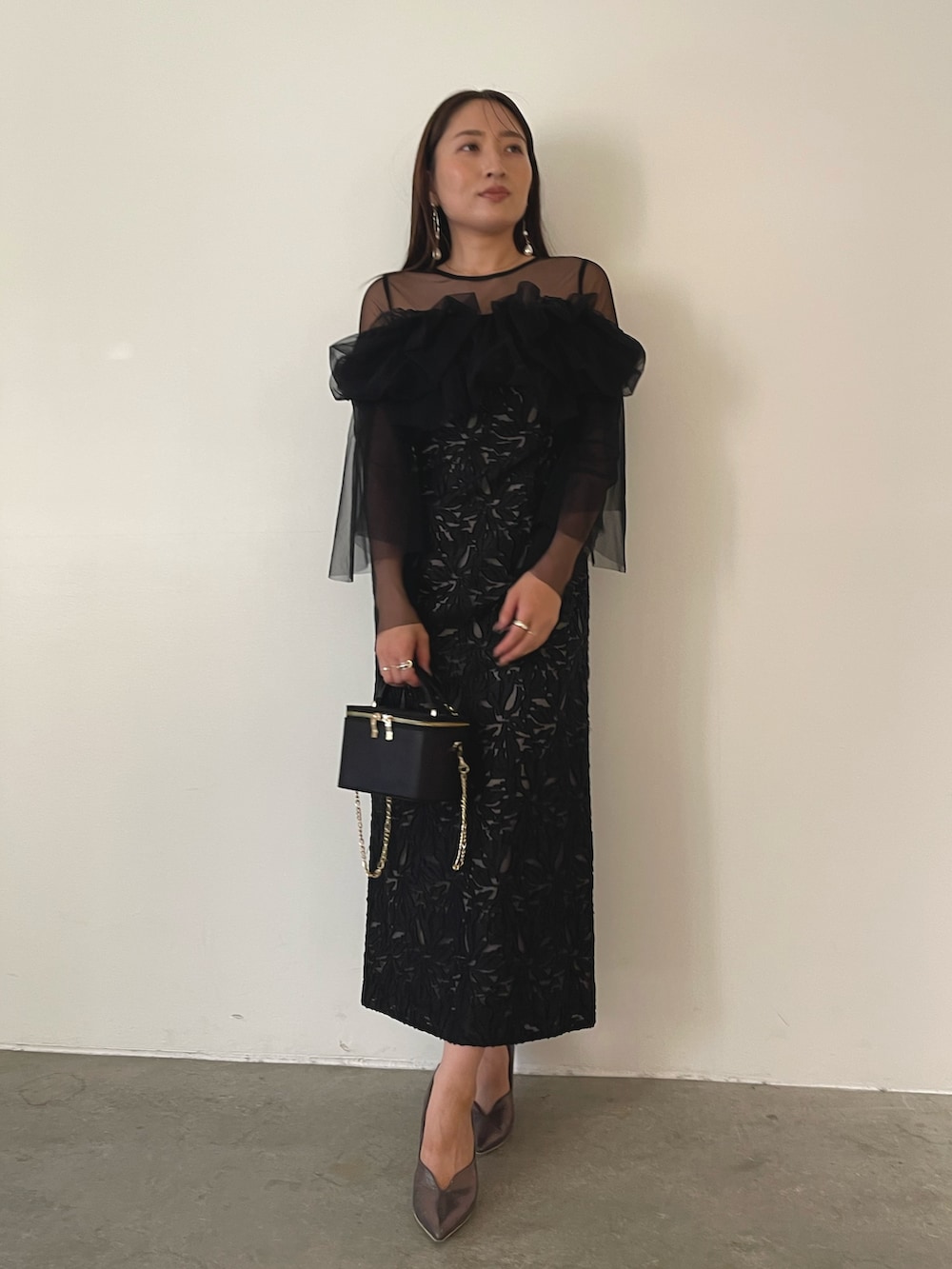 シルバー系のパンプス、ブラック系のハンドバッグ、ブラック系のドレスを着用したレディースの秋コーディネートの4枚目の写真