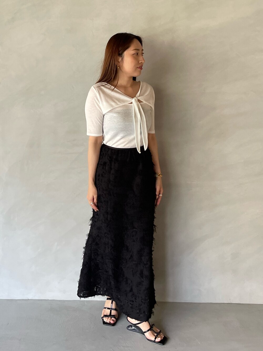 ブラック系のサンダル、ブラック系のスカート、ホワイト系のTシャツ/カットソーを着用したレディースの夏コーディネートの4枚目の写真