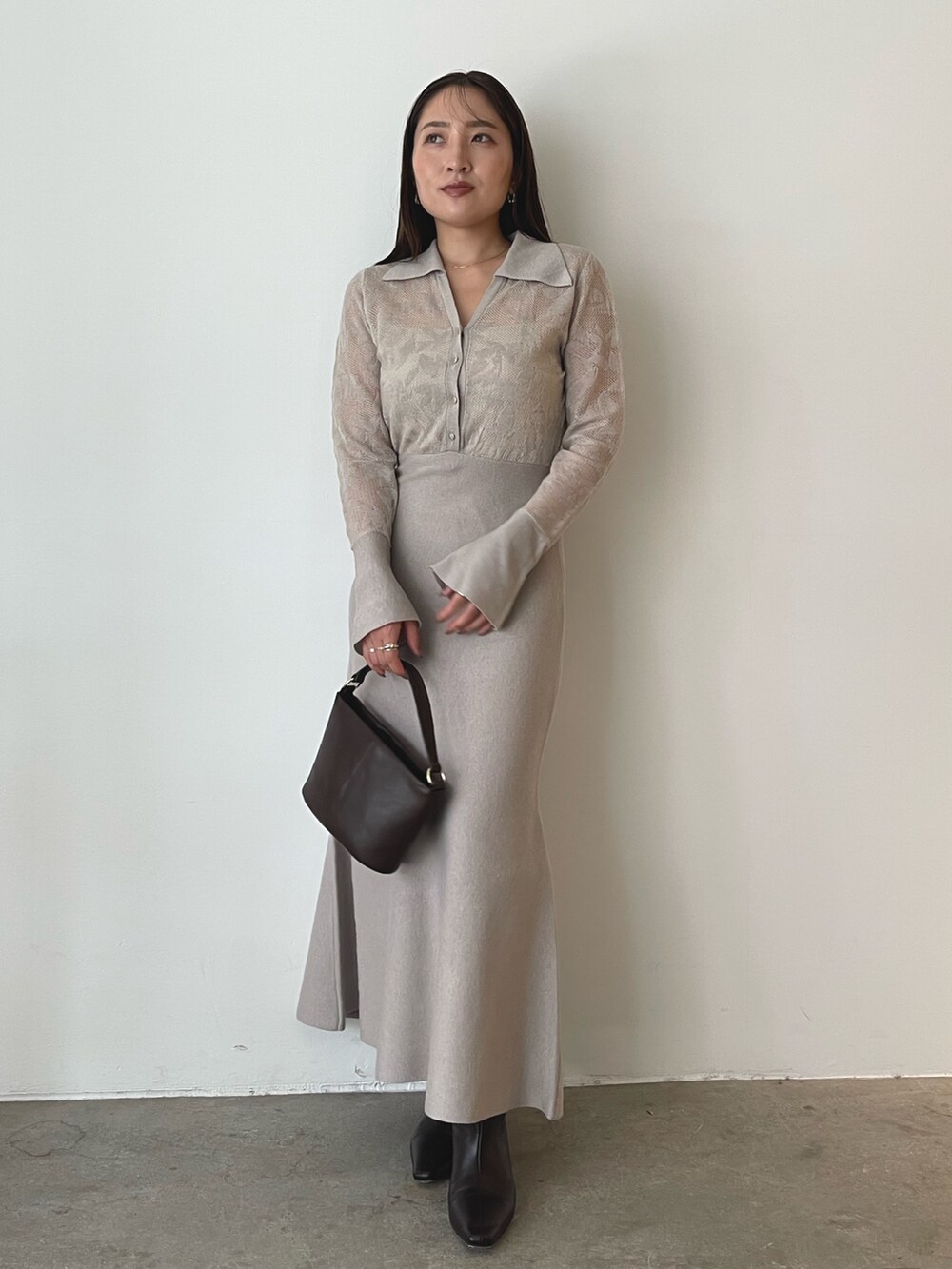 ブラウン系のハンドバッグ、ベージュ系のワンピース、ブラウン系のブーツを着用したレディースの秋コーディネートの7枚目の写真