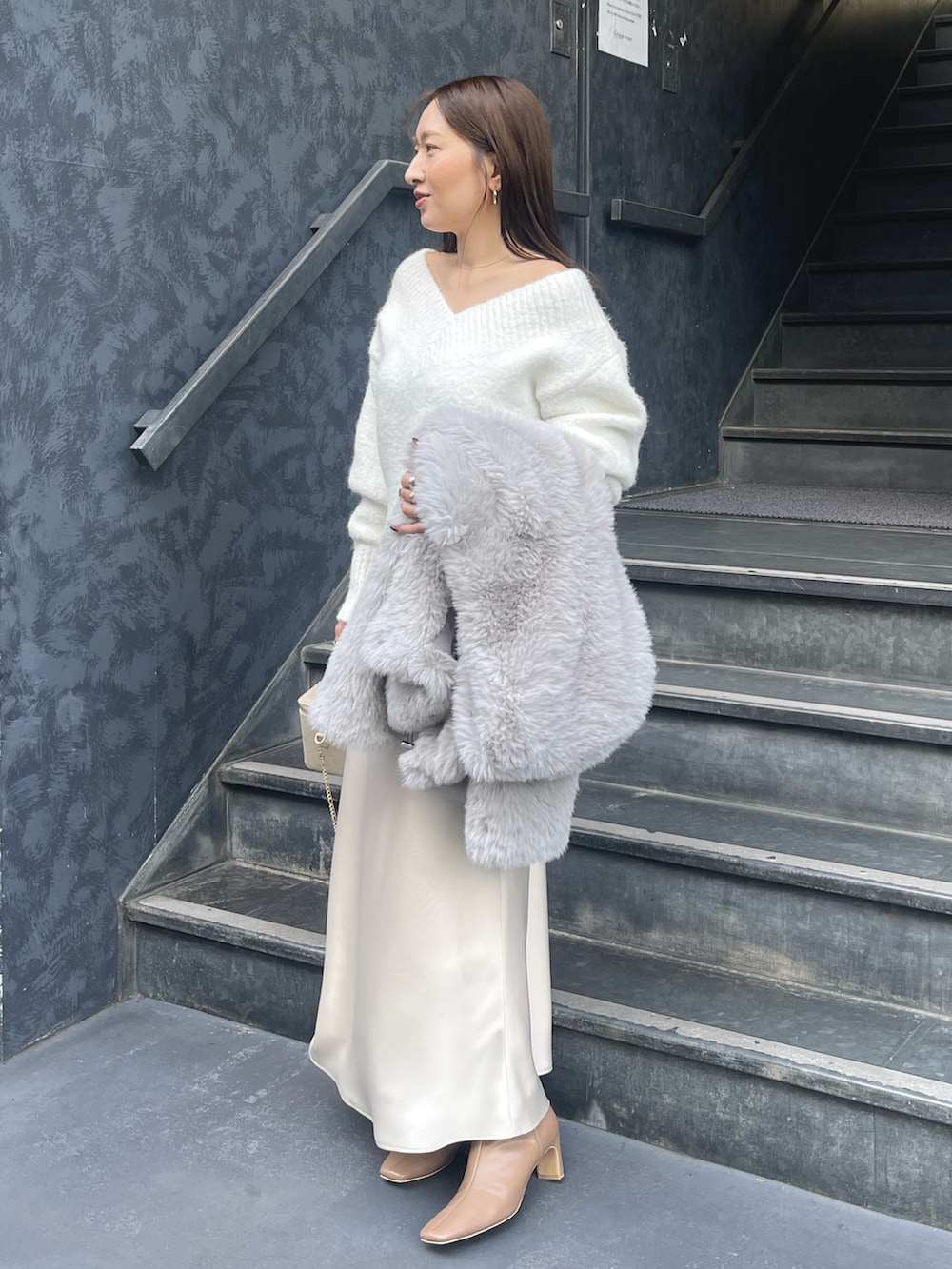 ホワイト系のニット/セーター、グレー系のその他アウター、ゴールド系のハンドバッグを着用したレディースの冬コーディネートの6枚目の写真