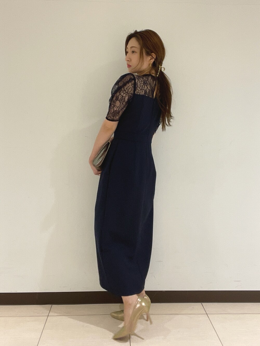 ブルー系のドレス、ゴールド系のハンドバッグ、ゴールド系のパンプスを着用したレディースの夏コーディネートの7枚目の写真