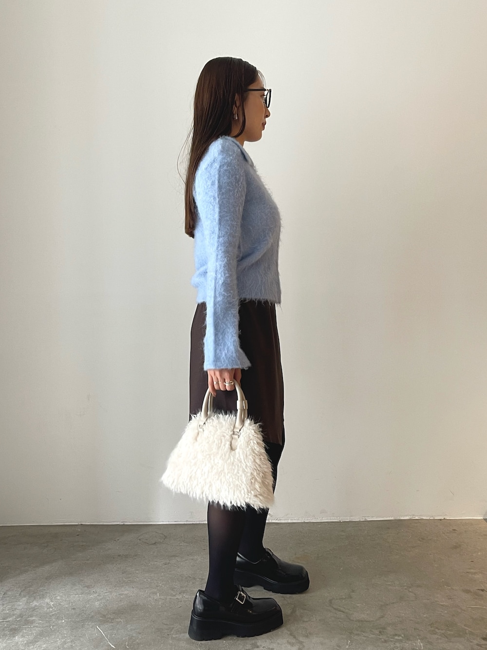 ホワイト系のボストンバッグ、ブラウン系のスカート、ブラック系のローファーを着用したレディースの秋コーディネートの4枚目の写真