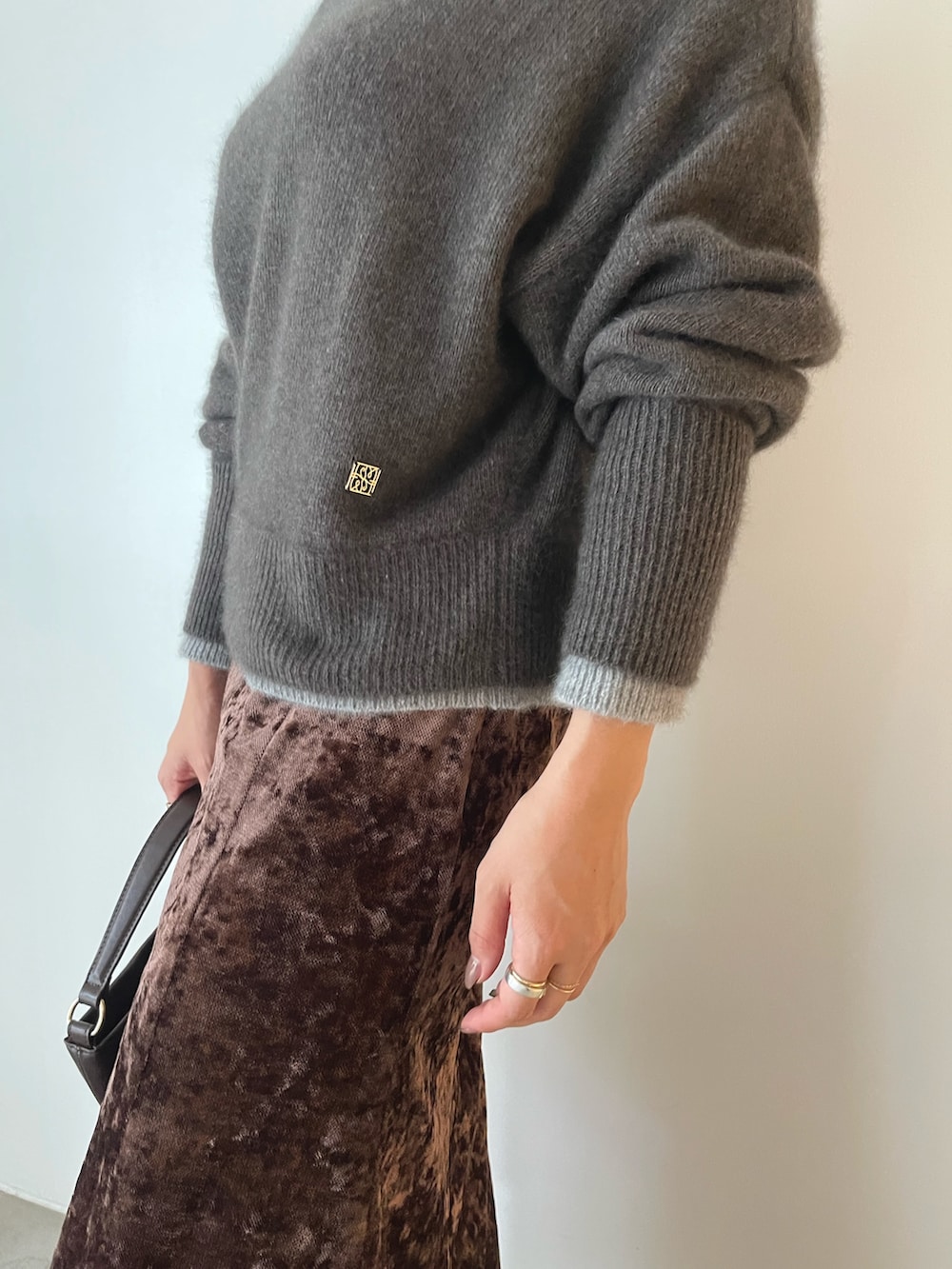 ブラウン系のハンドバッグ、ブラウン系のニット/セーター、ブラウン系のスカートを着用したレディースの秋コーディネートの7枚目の写真