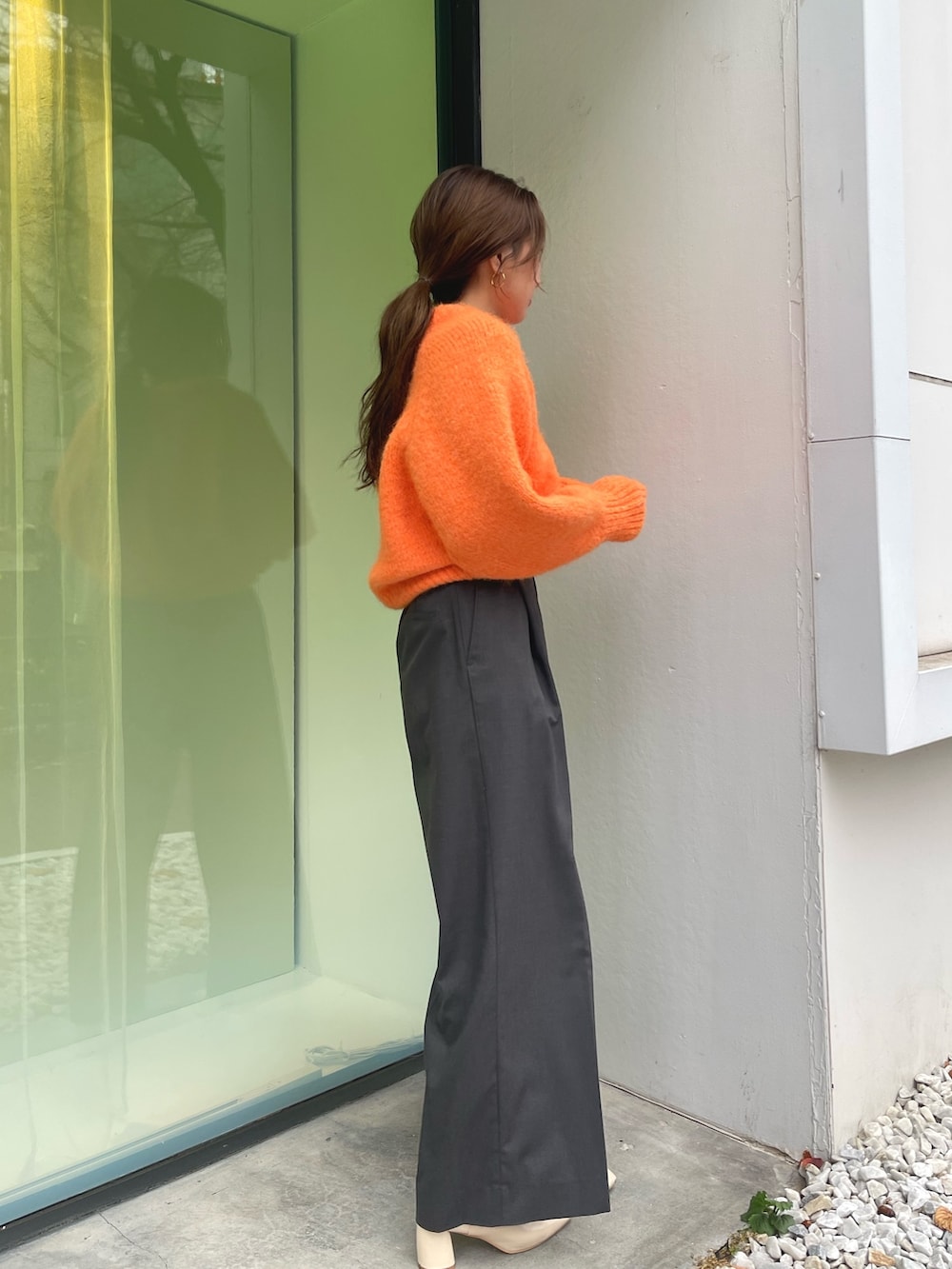 オレンジ系のニット/セーター、グレー系のその他パンツ、ホワイト系のブーツを着用したレディースの冬コーディネートの6枚目の写真