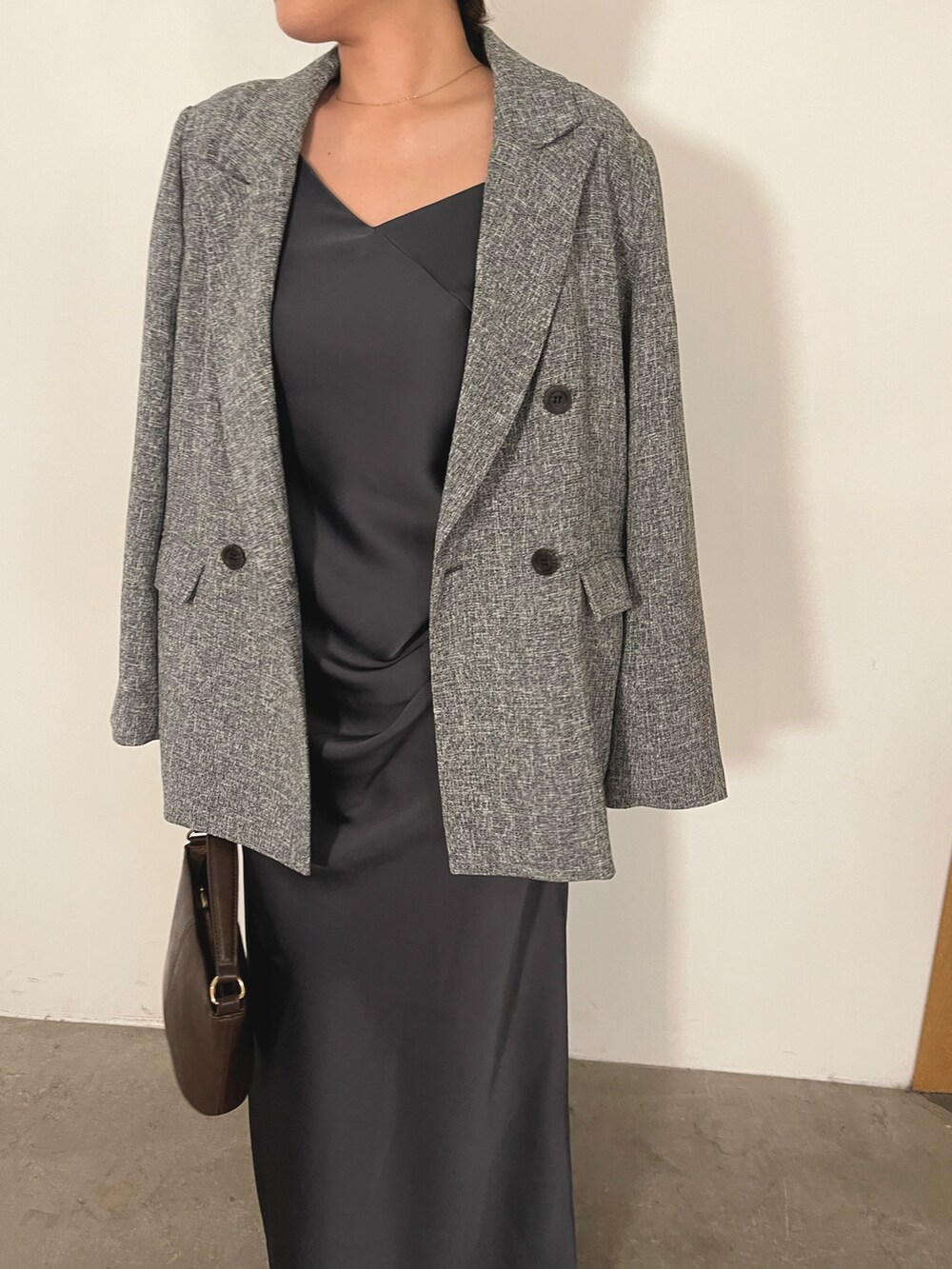 グレー系のドレス、ブラウン系のハンドバッグ、ゴールド系のパンプスを着用したレディースの冬コーディネートの10枚目の写真