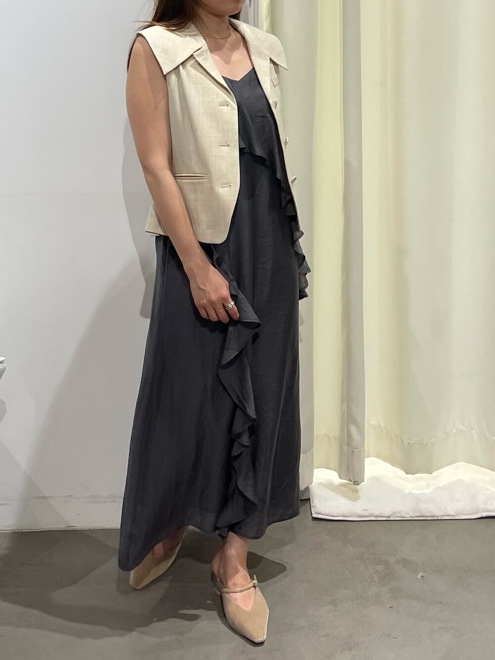 ホワイト系のベスト、グレー系のワンピース、ベージュ系のパンプスを着用したレディースの夏コーディネートの9枚目の写真