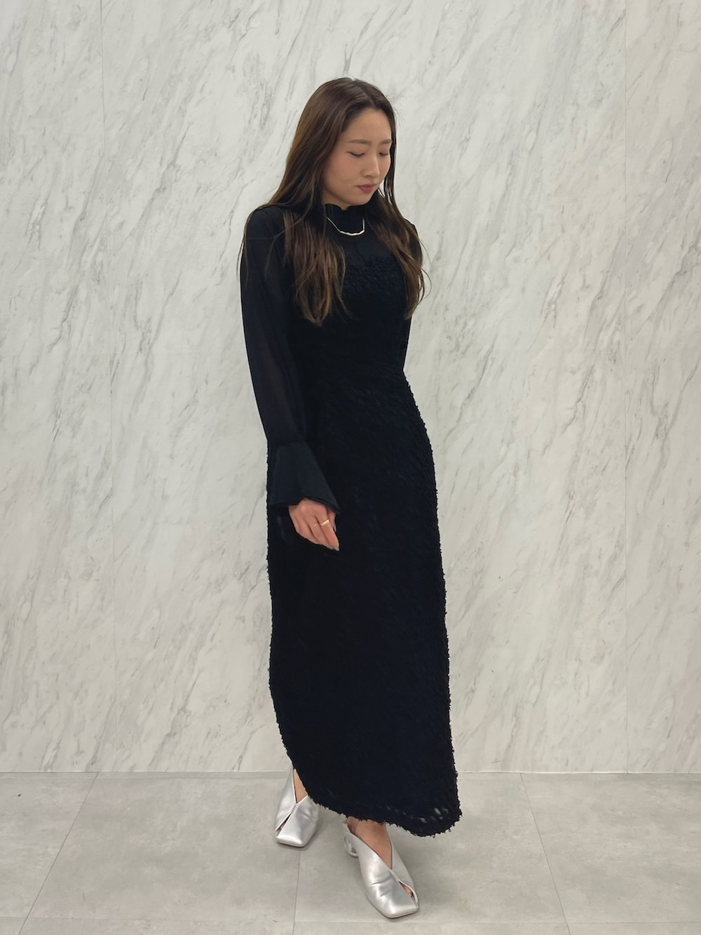 シルバー系のパンプス、ブラック系のワンピース、ゴールド系のネックレスを着用したレディースの春コーディネートの2枚目の写真